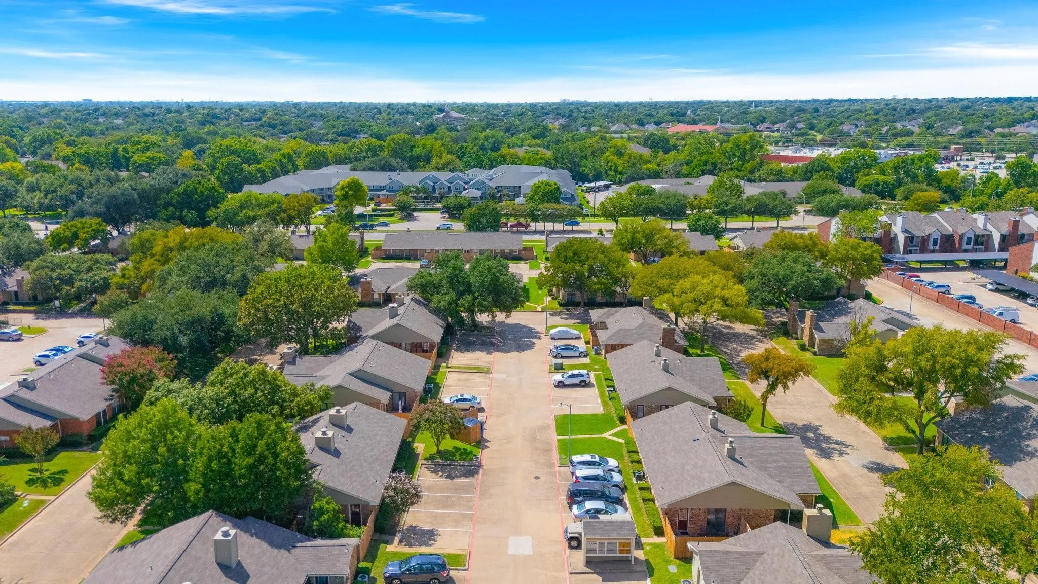 Expansive property featuring multiple single-story and multi-story buildings, mature trees, dedicated surface parking, and paved roadways