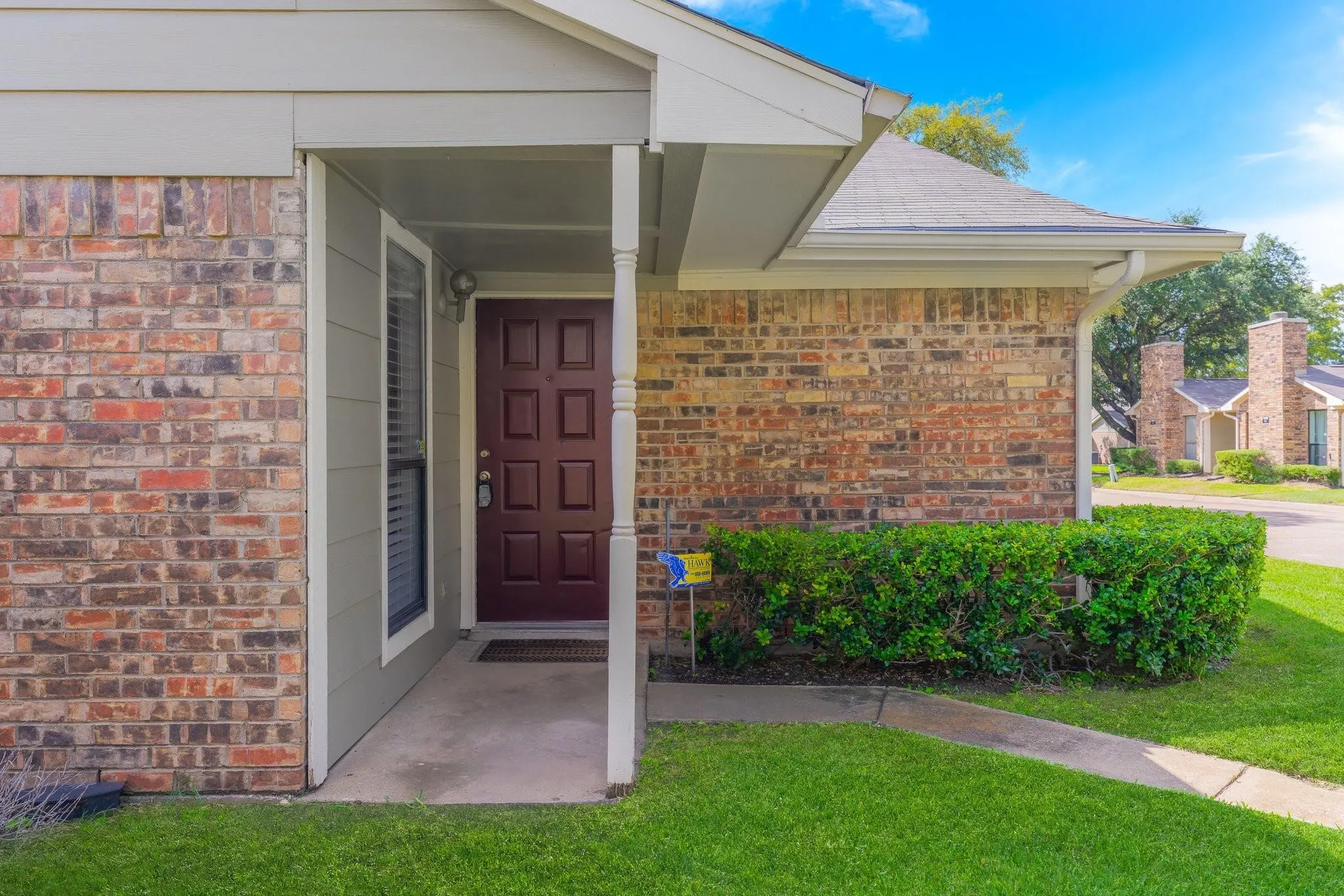 Brick facade with light siding accents, covered entry porch, and a paneled entry door