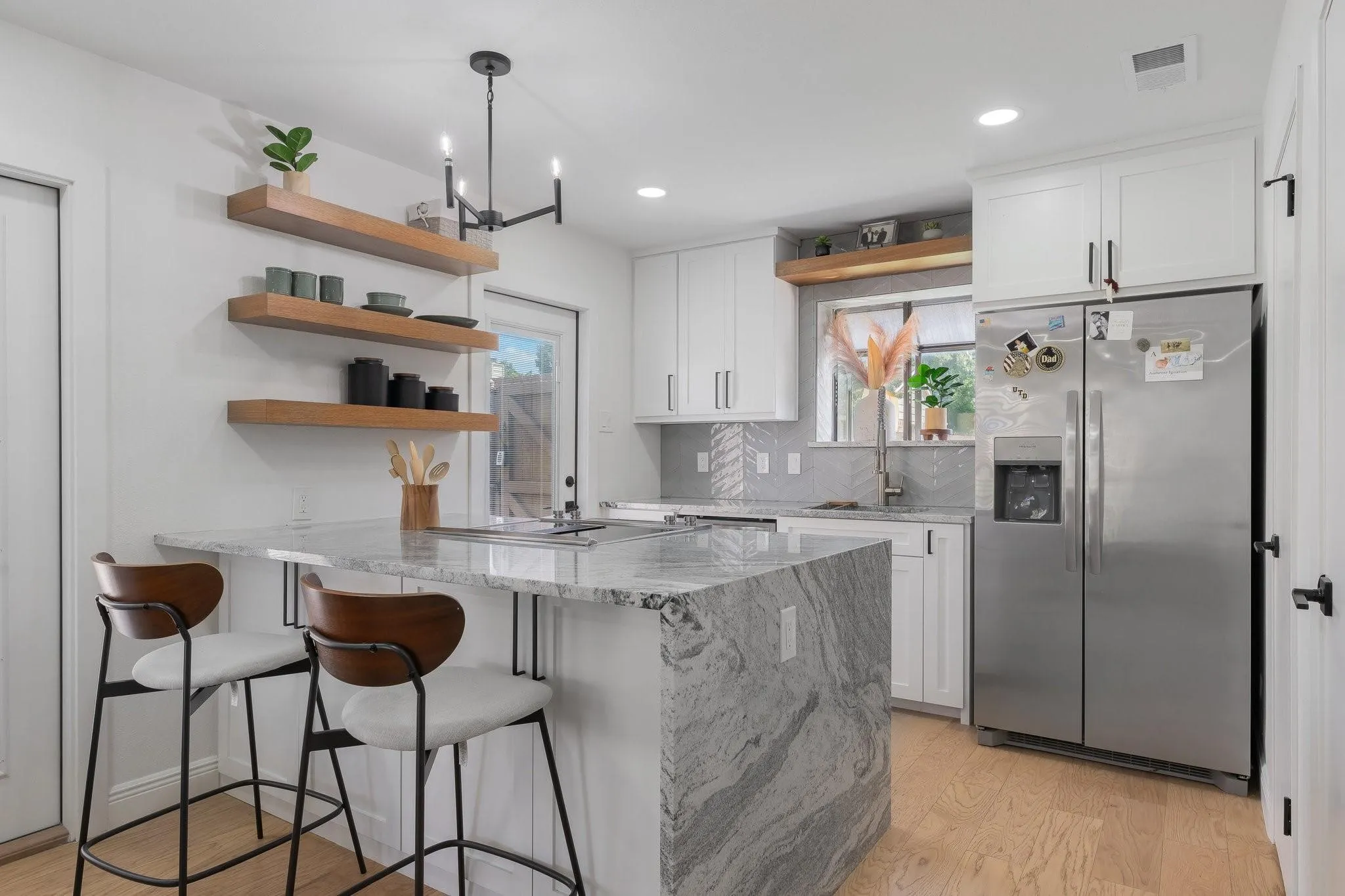 Kitchen featuring a waterfall island, white cabinetry, stainless steel refrigerator, light wood-finish flooring, and open shelving