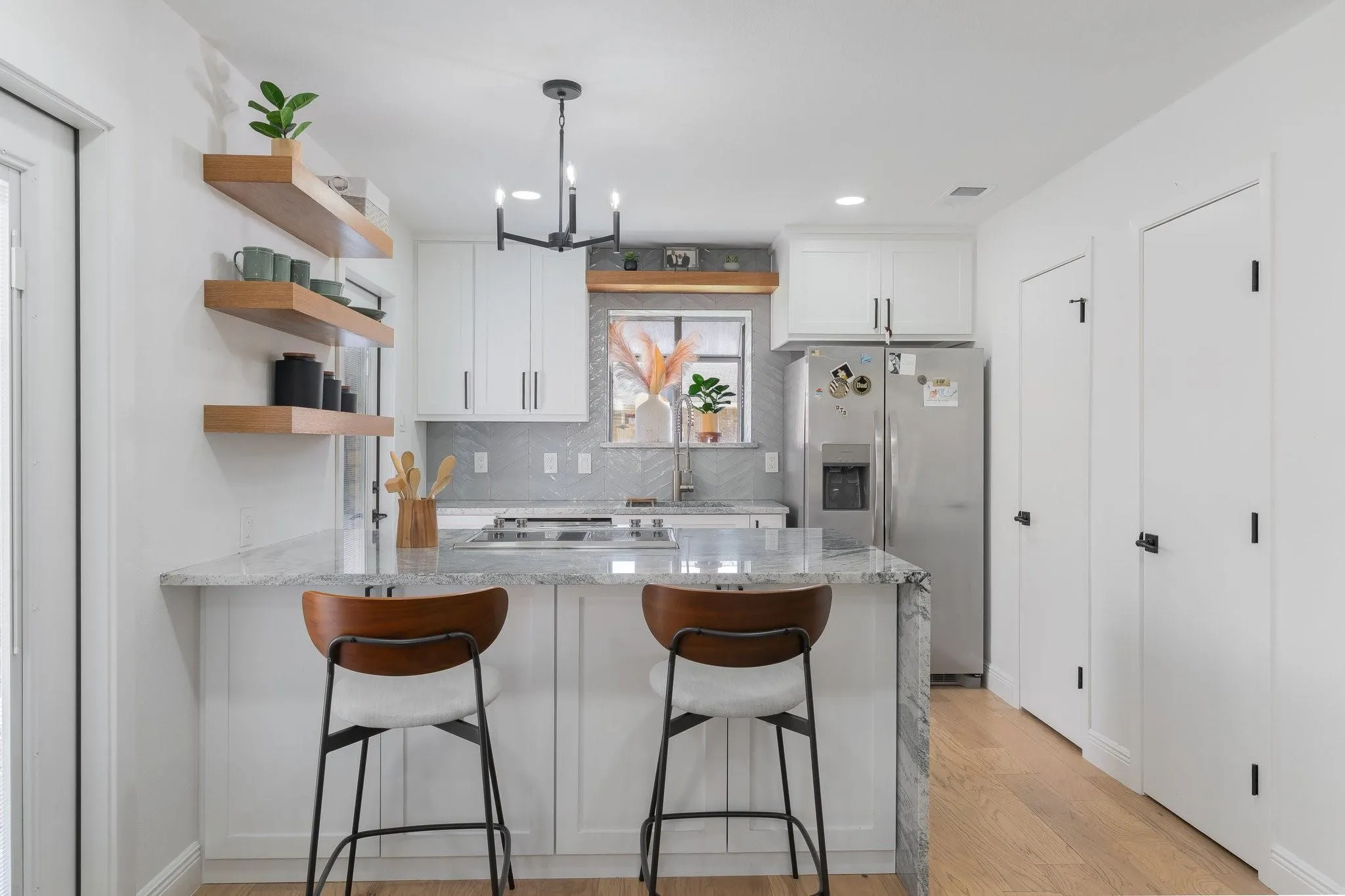 Kitchen featuring white cabinetry, light-toned wood-finish flooring, a central island with a light-colored countertop, and a stainless steel refrigerator
