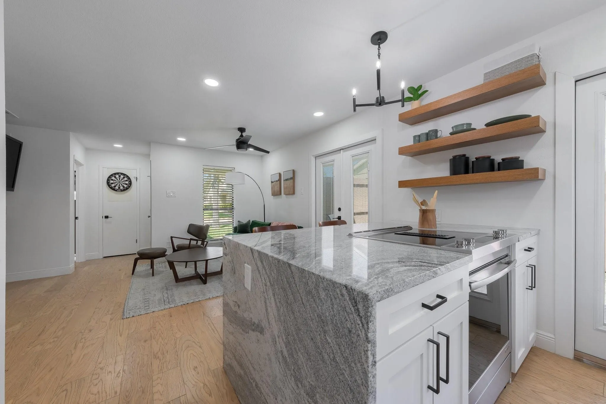 Kitchen island with a waterfall countertop, built-in cooktop, and integrated oven