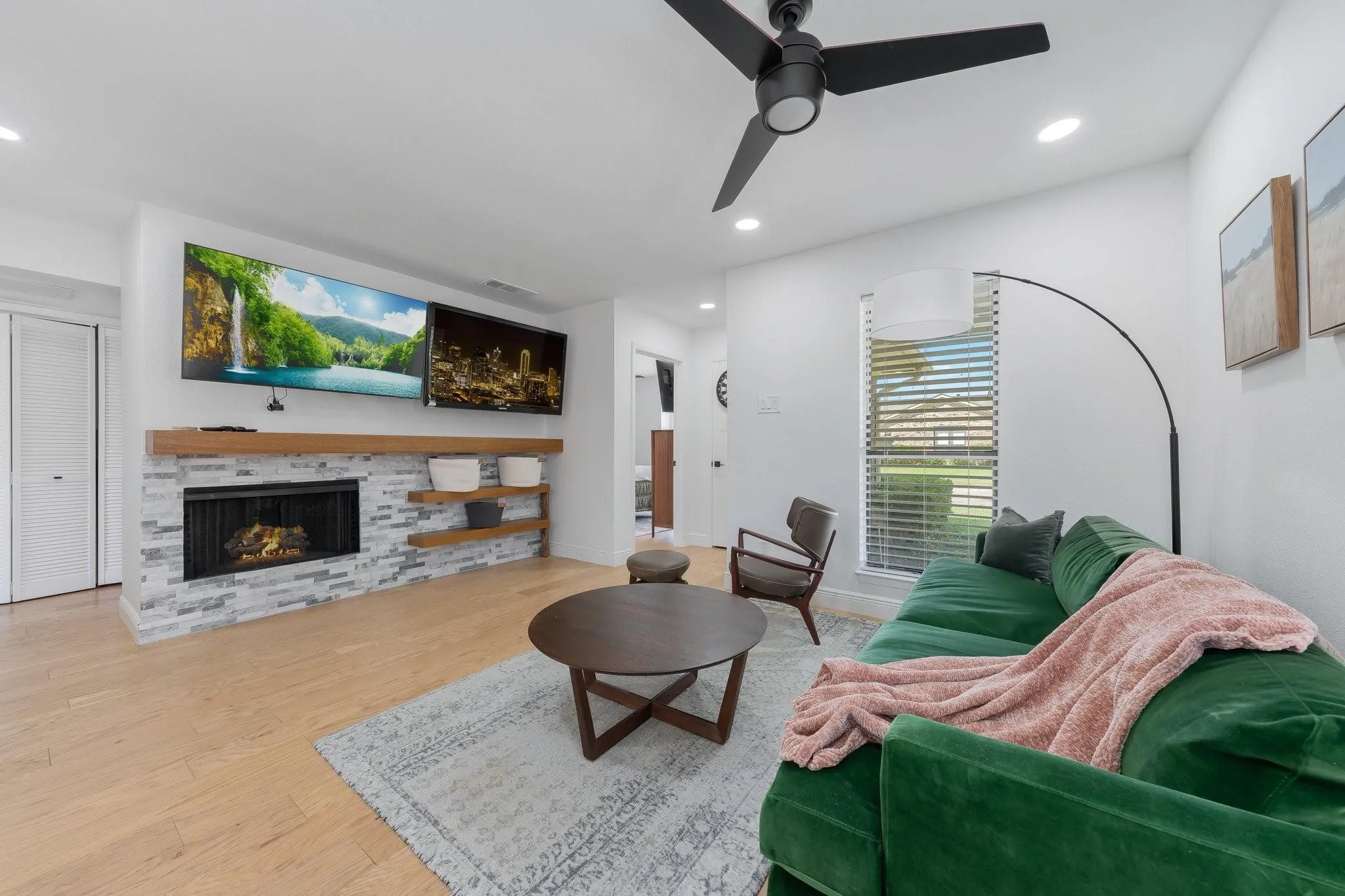 Wood-finish flooring, recessed lighting, and a black ceiling fan complement the white walls