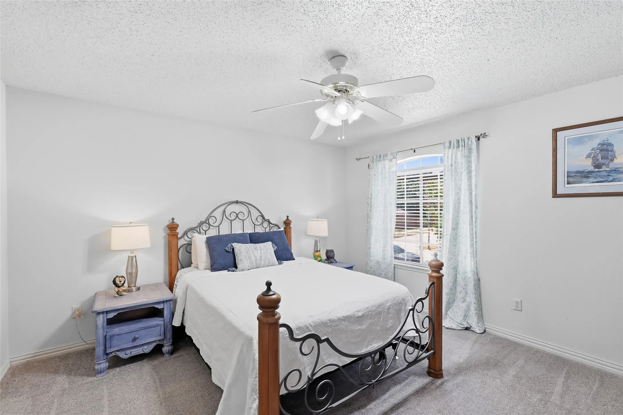 Ceiling fan with integrated lighting, window with horizontal blinds, textured ceiling, light-colored walls, and gray carpeting