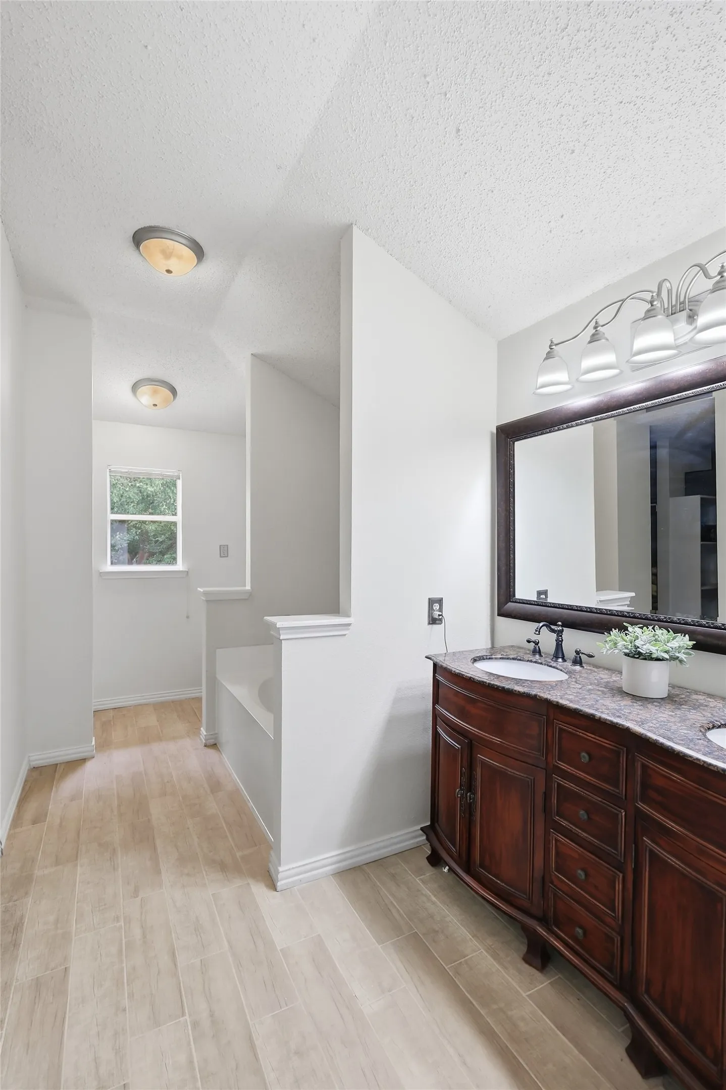 Double vanity with integrated sinks, framed mirror, and contemporary sconce lighting