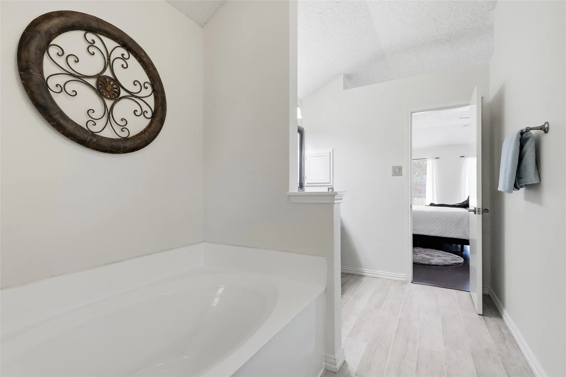 Built-in soaking tub, vaulted ceiling, and wood-finish flooring