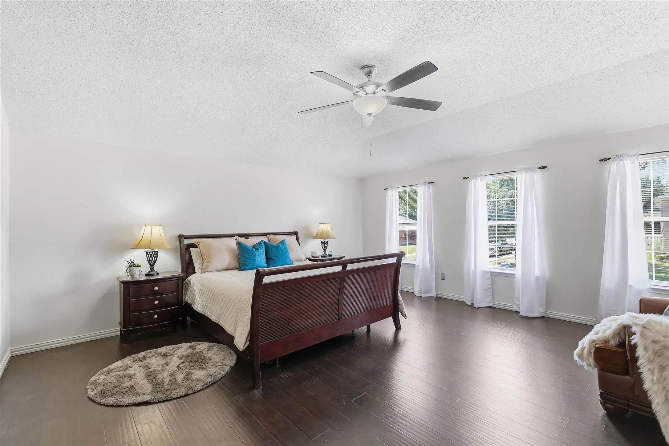 Spacious room featuring wood-finish flooring, multiple windows, and a ceiling fan