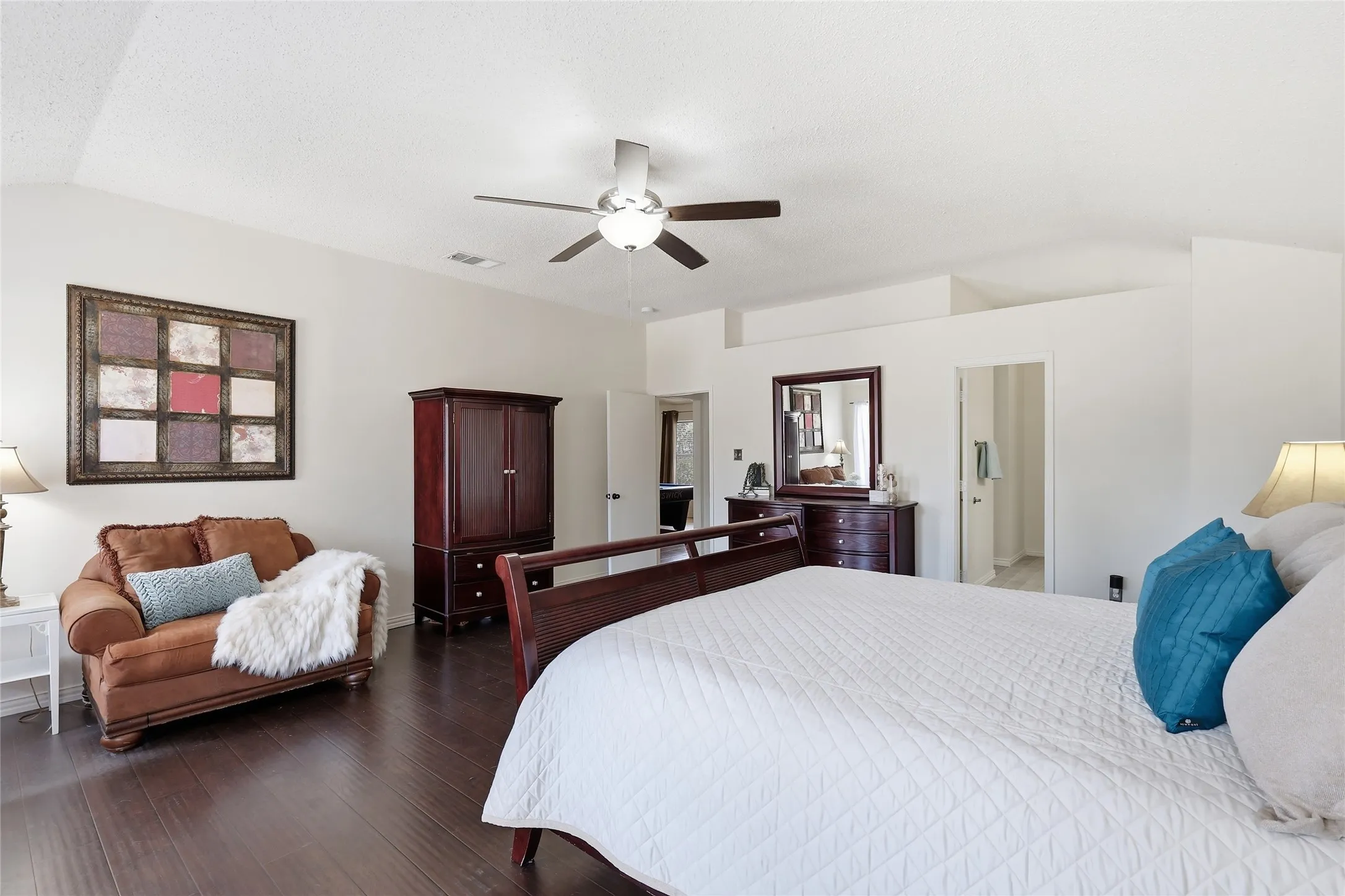 Vaulted ceiling, wood-finish flooring, ceiling fan with integrated lighting, and white walls