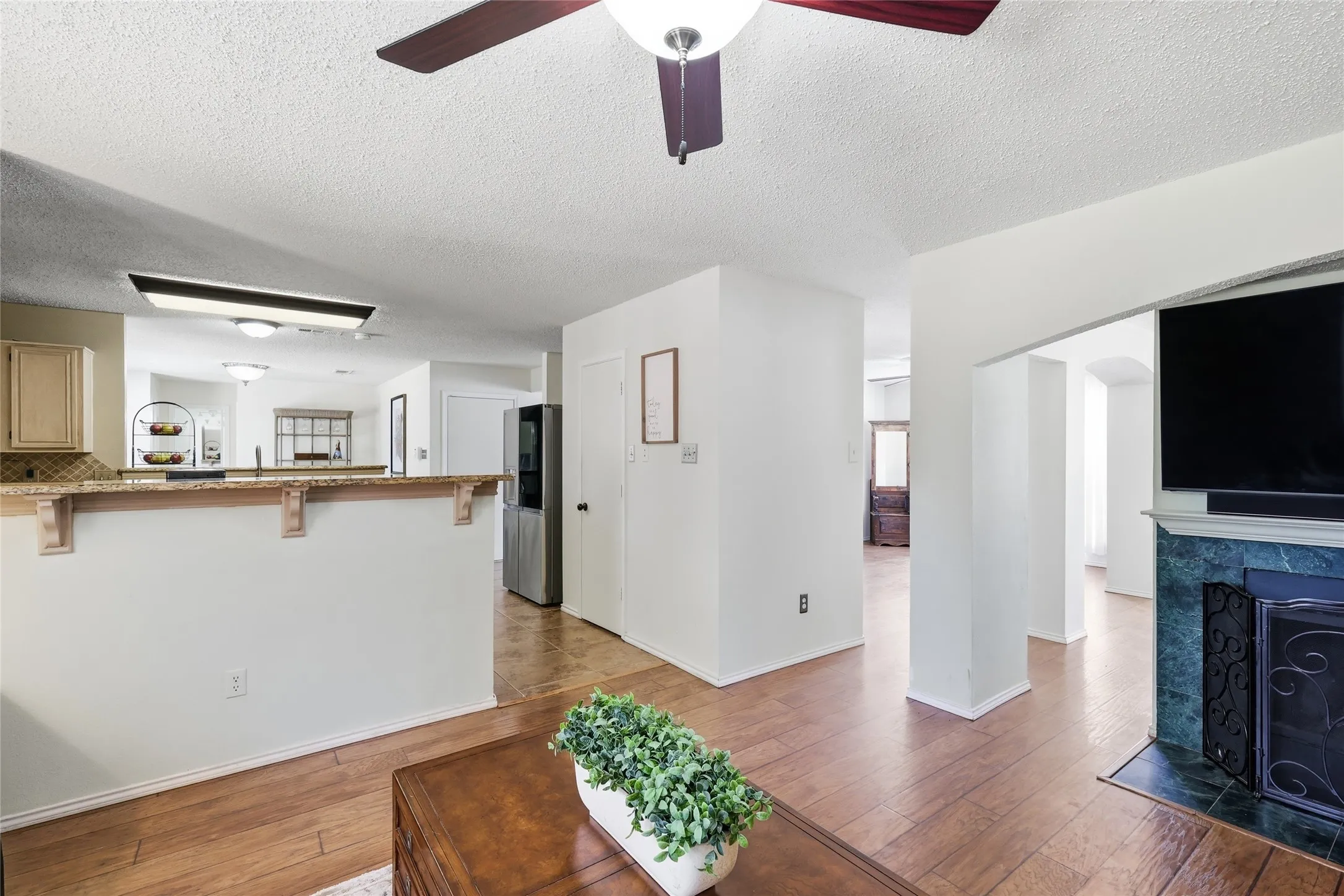 Wood-finish flooring throughout, with a built-in fireplace featuring a decorative screen and a dark green surround