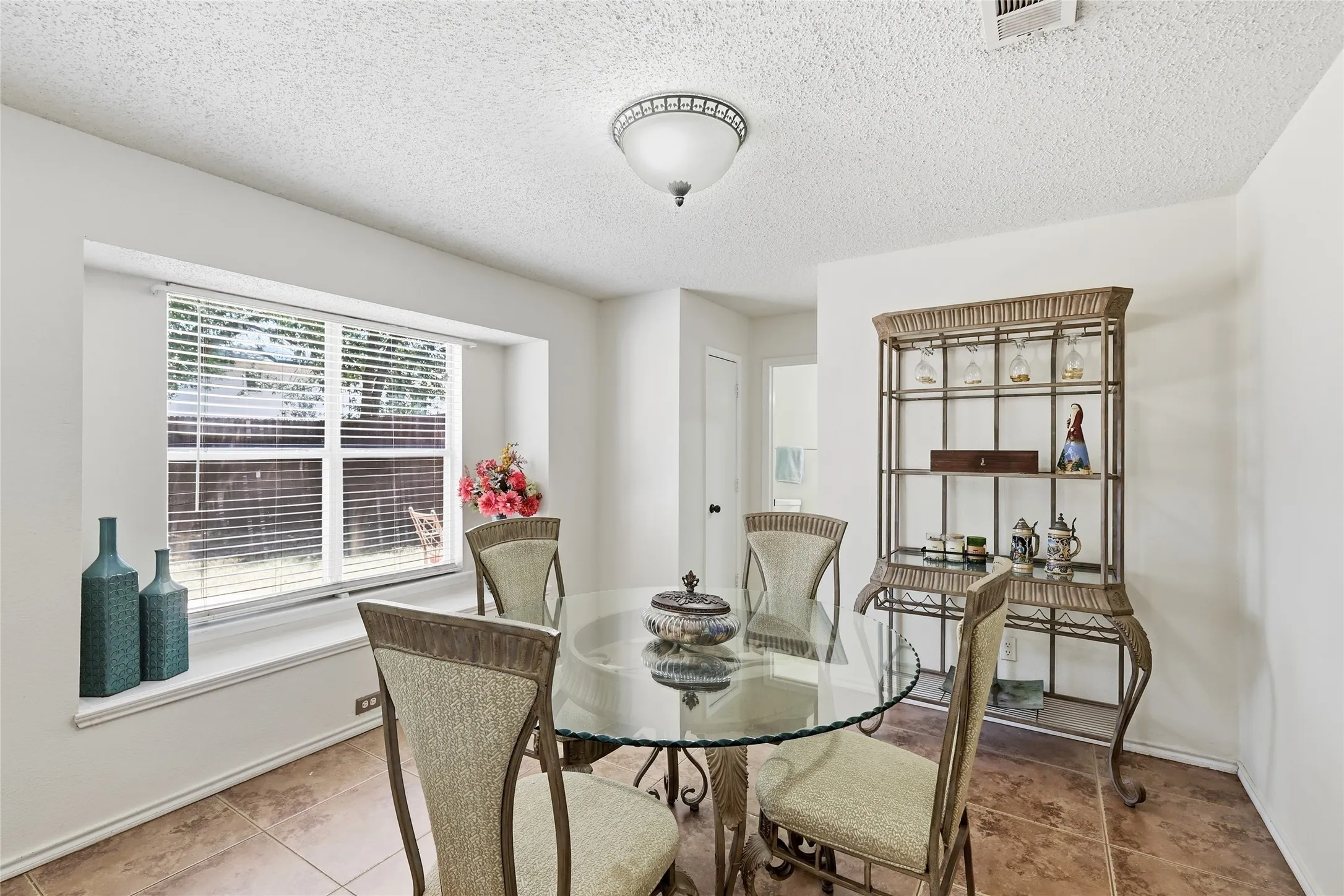 Recessed window with horizontal blinds, tiled flooring, textured ceiling, and a ceiling-mounted light fixture