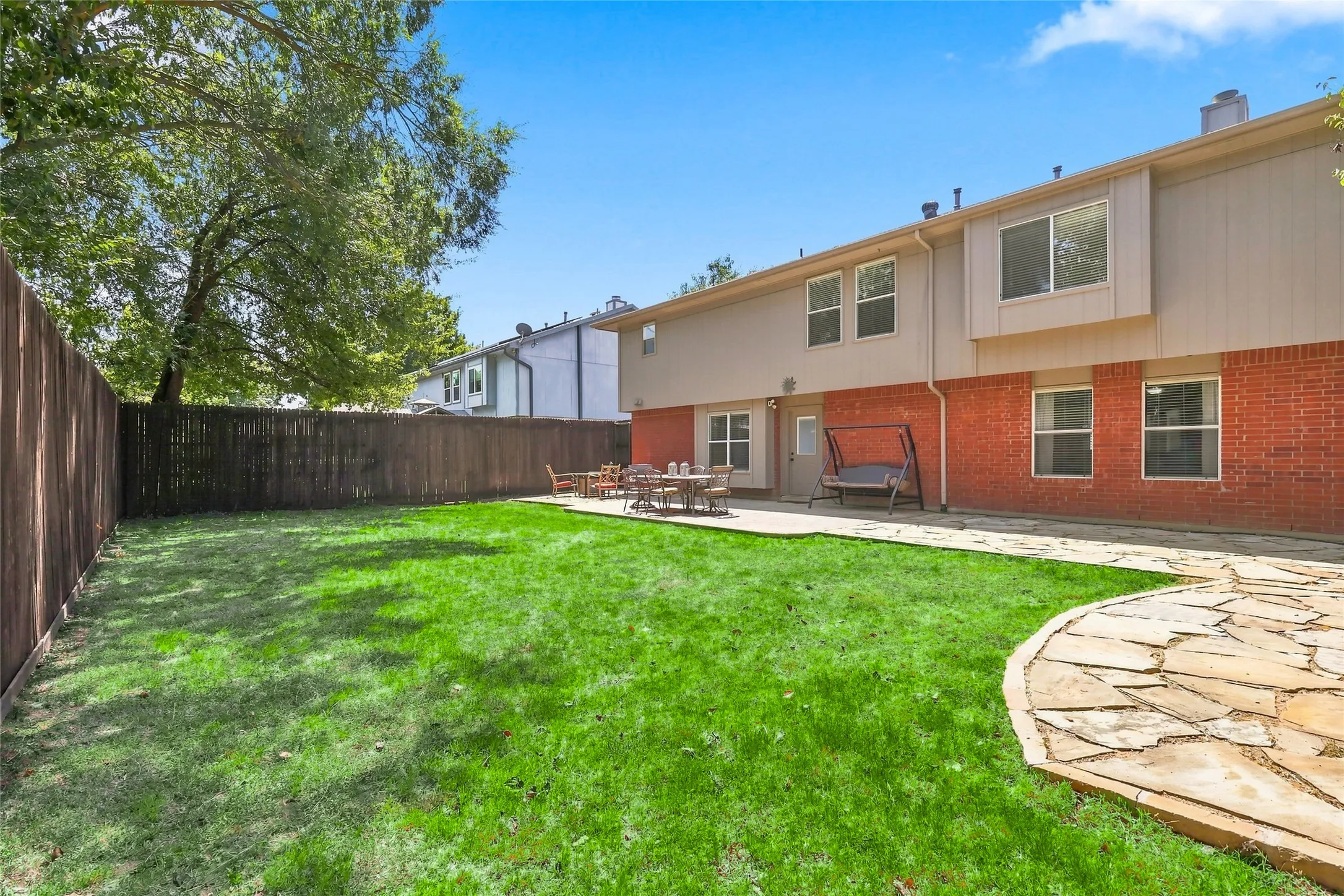 Expansive backyard with a manicured lawn, flagstone patio, and privacy fencing
