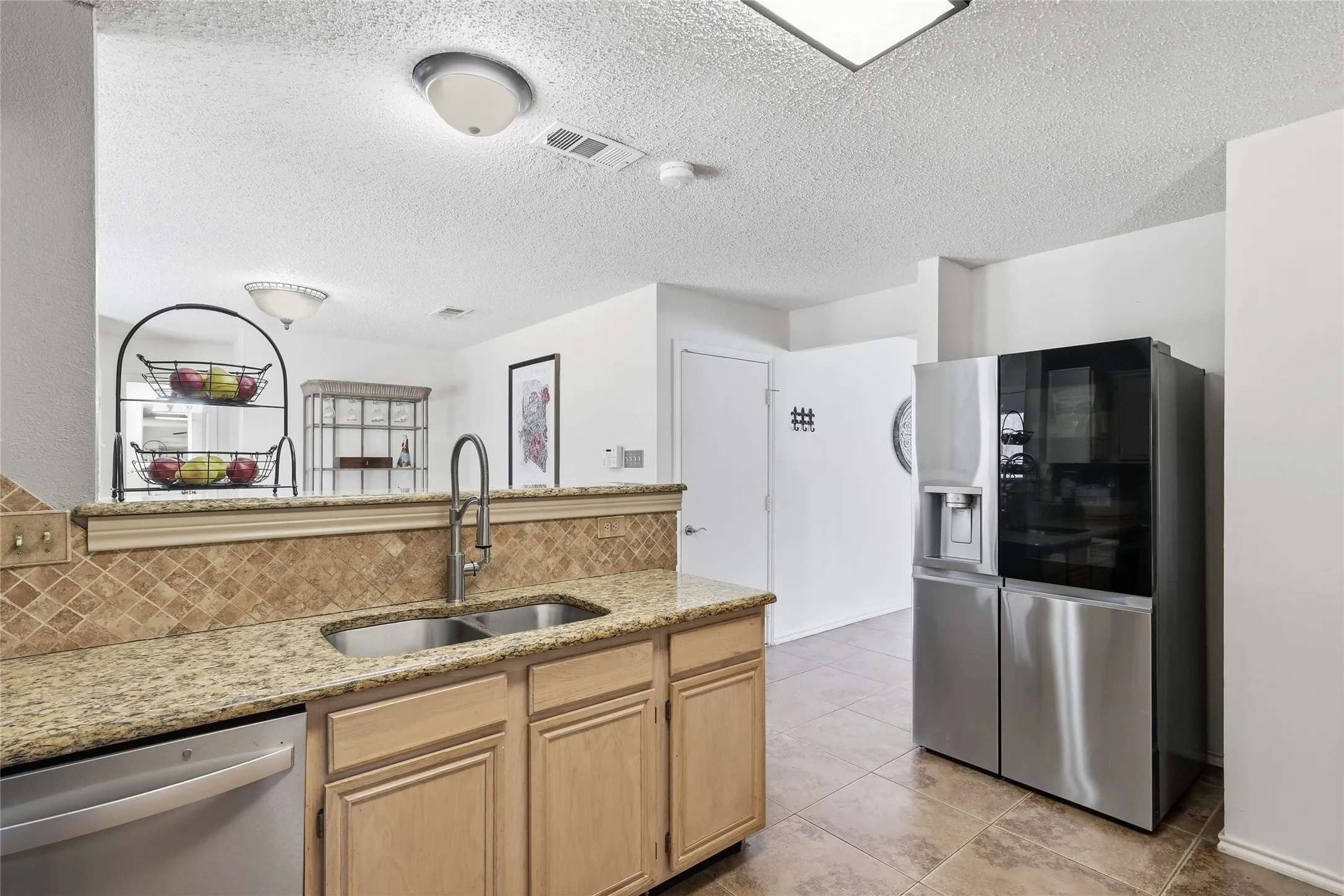 Kitchen featuring granite countertops, wood cabinetry, stainless steel sink with gooseneck faucet, diamond-patterned tile backsplash, and tile flooring
