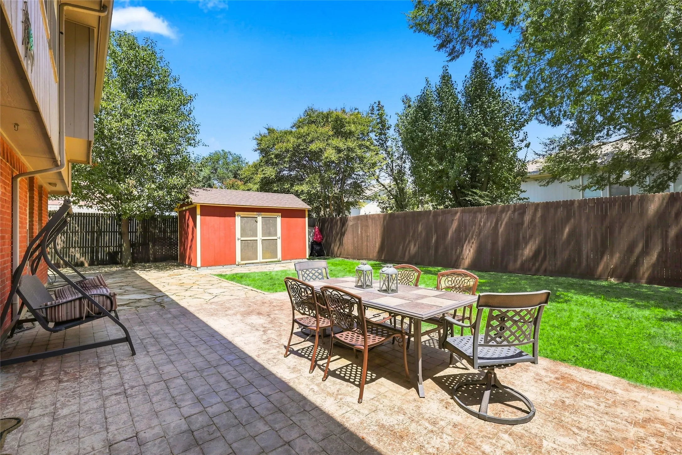 Expansive paver patio with a separate storage shed and manicured lawn