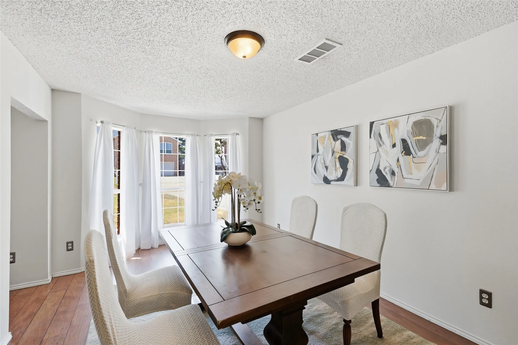 Bay window with multiple panes, wood-finish flooring, white walls, and an overhead flush mount light fixture