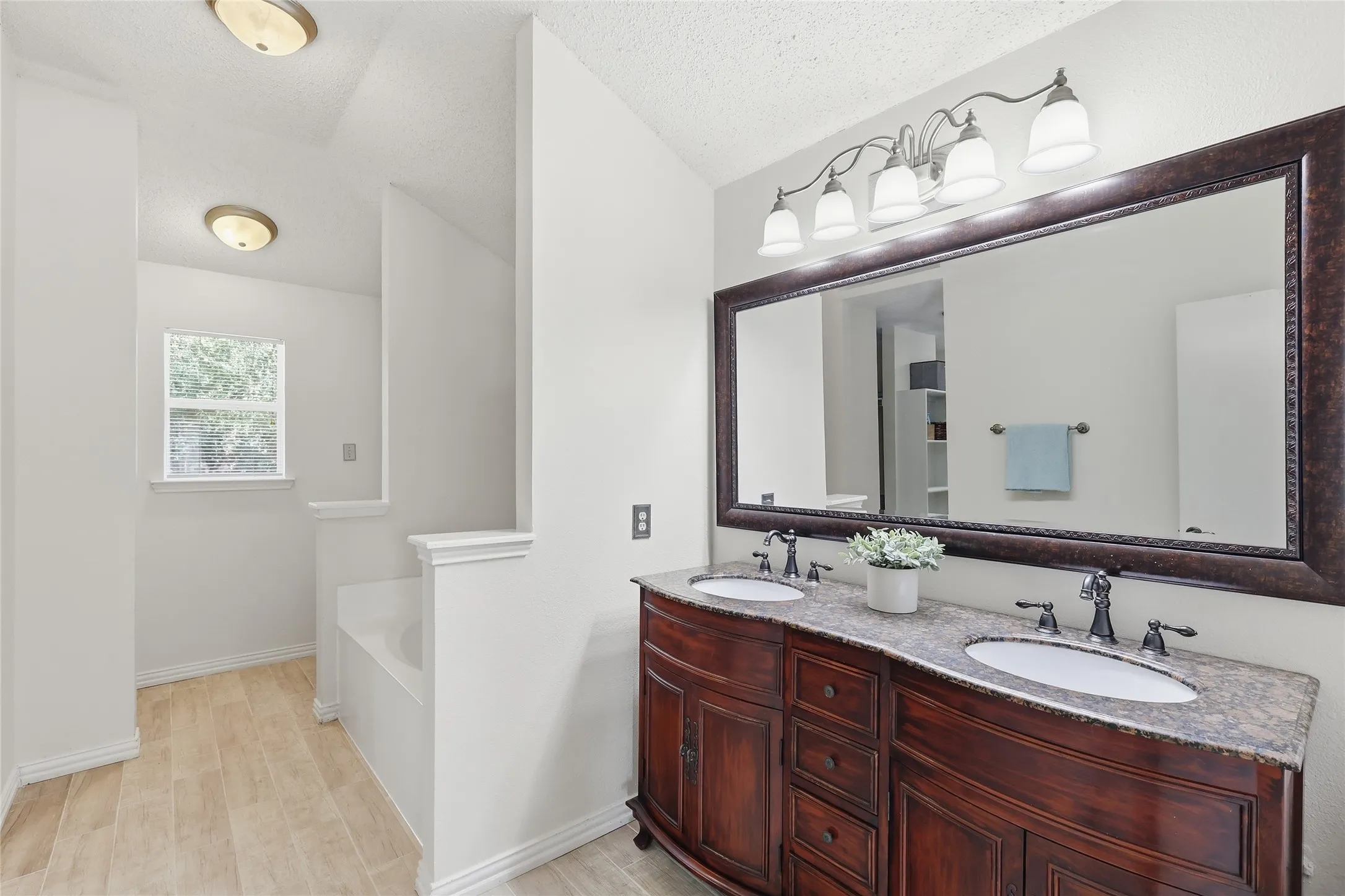 Dual vanity with dark wood-finish cabinetry, under-mount sinks, and a stone-finish countertop