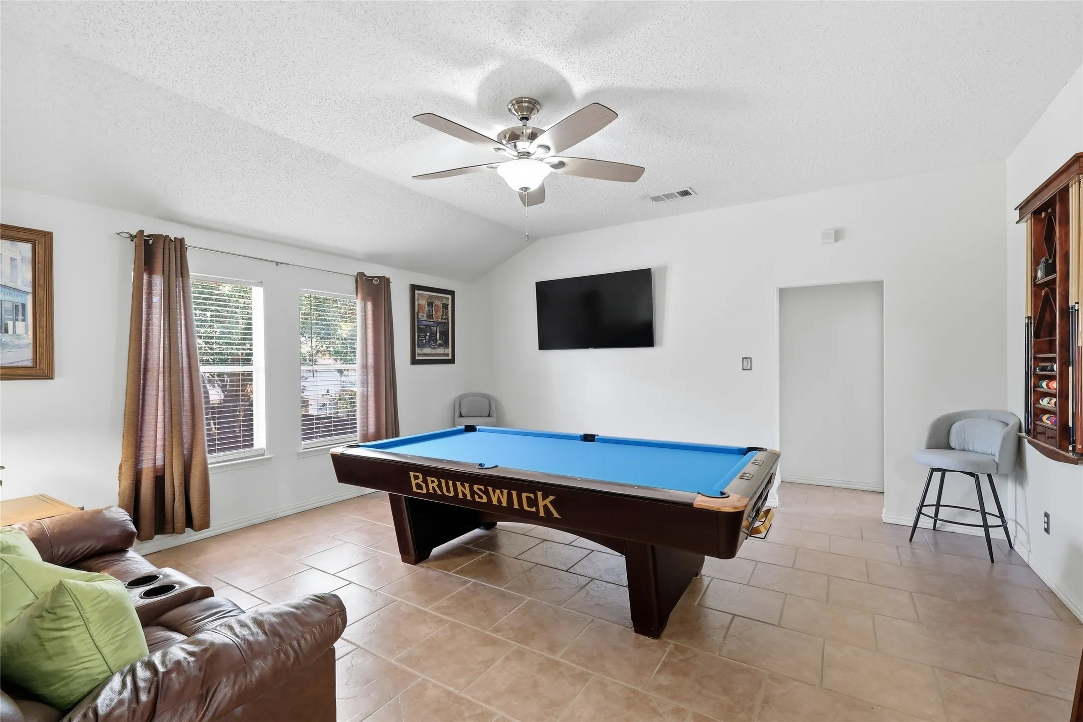Vaulted ceiling with ceiling fan, tile flooring, and multiple windows with blinds