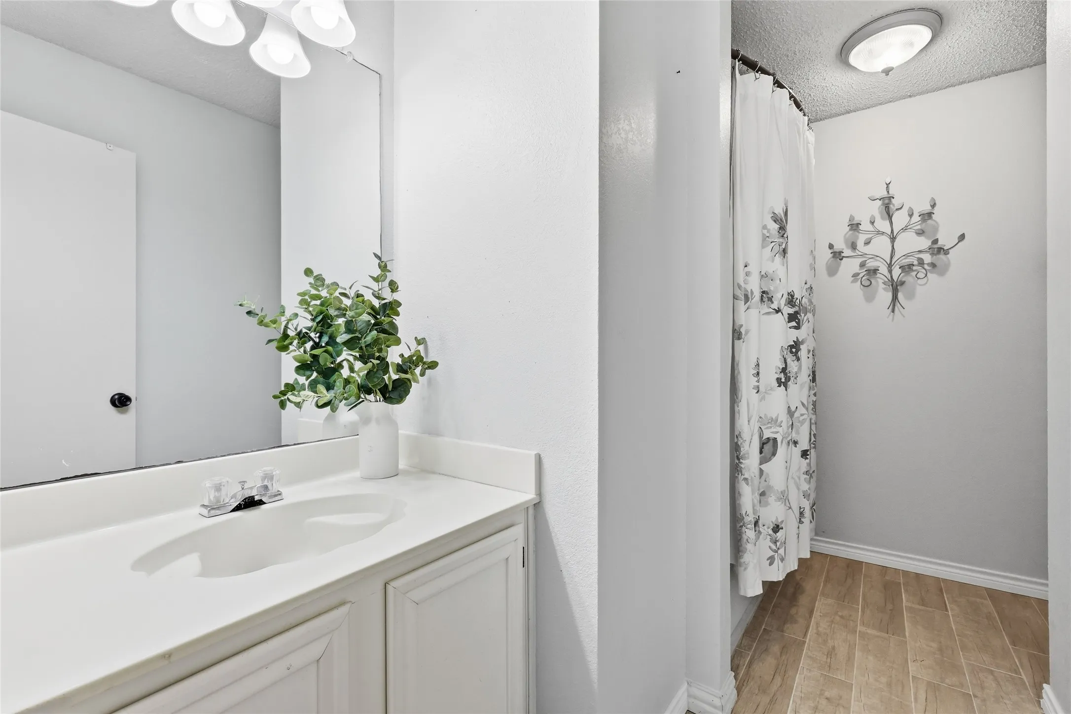 Vanity with integrated sink, white cabinetry, and wall-mounted mirror