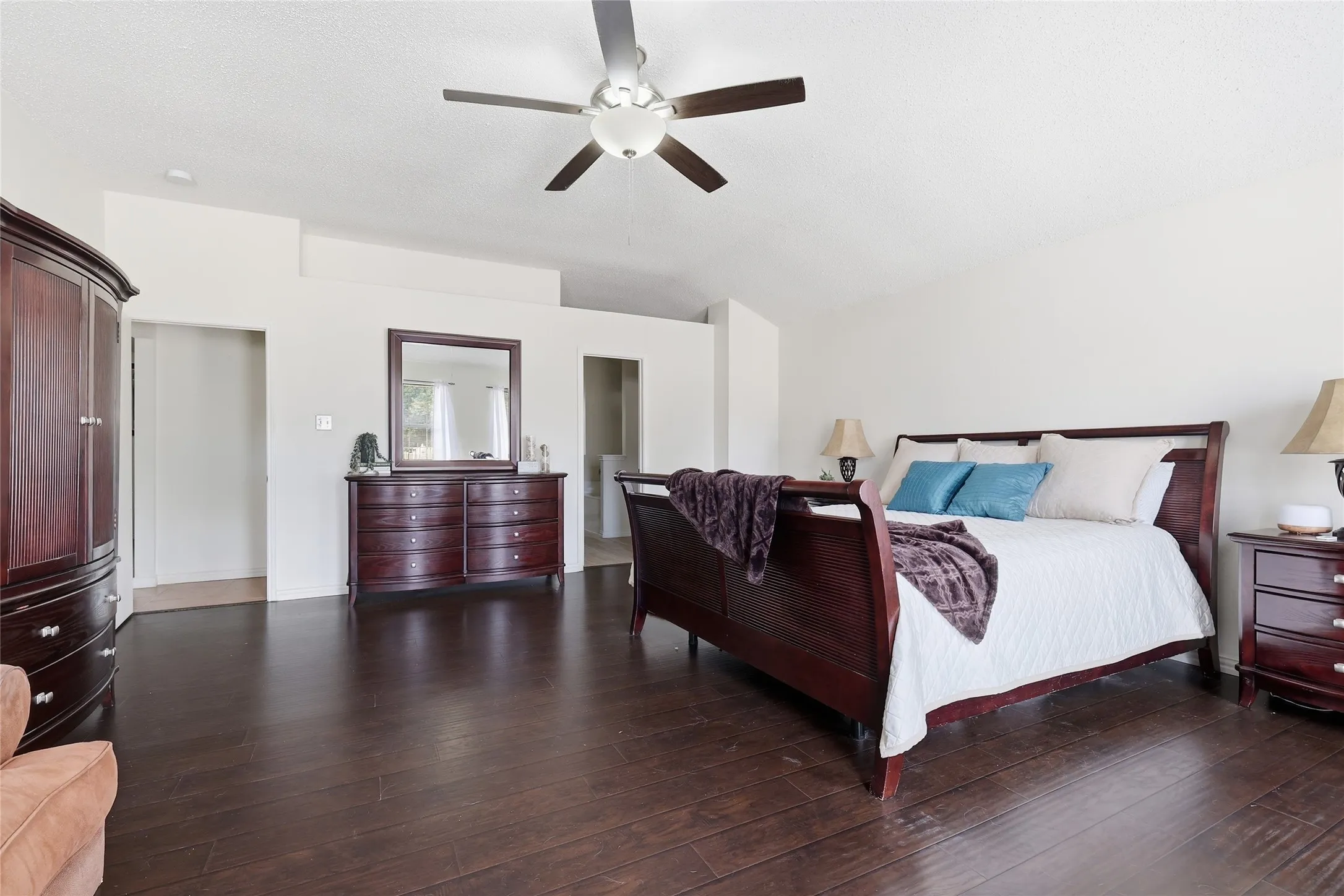 Dark wood-finish flooring with a ceiling fan and recessed lighting