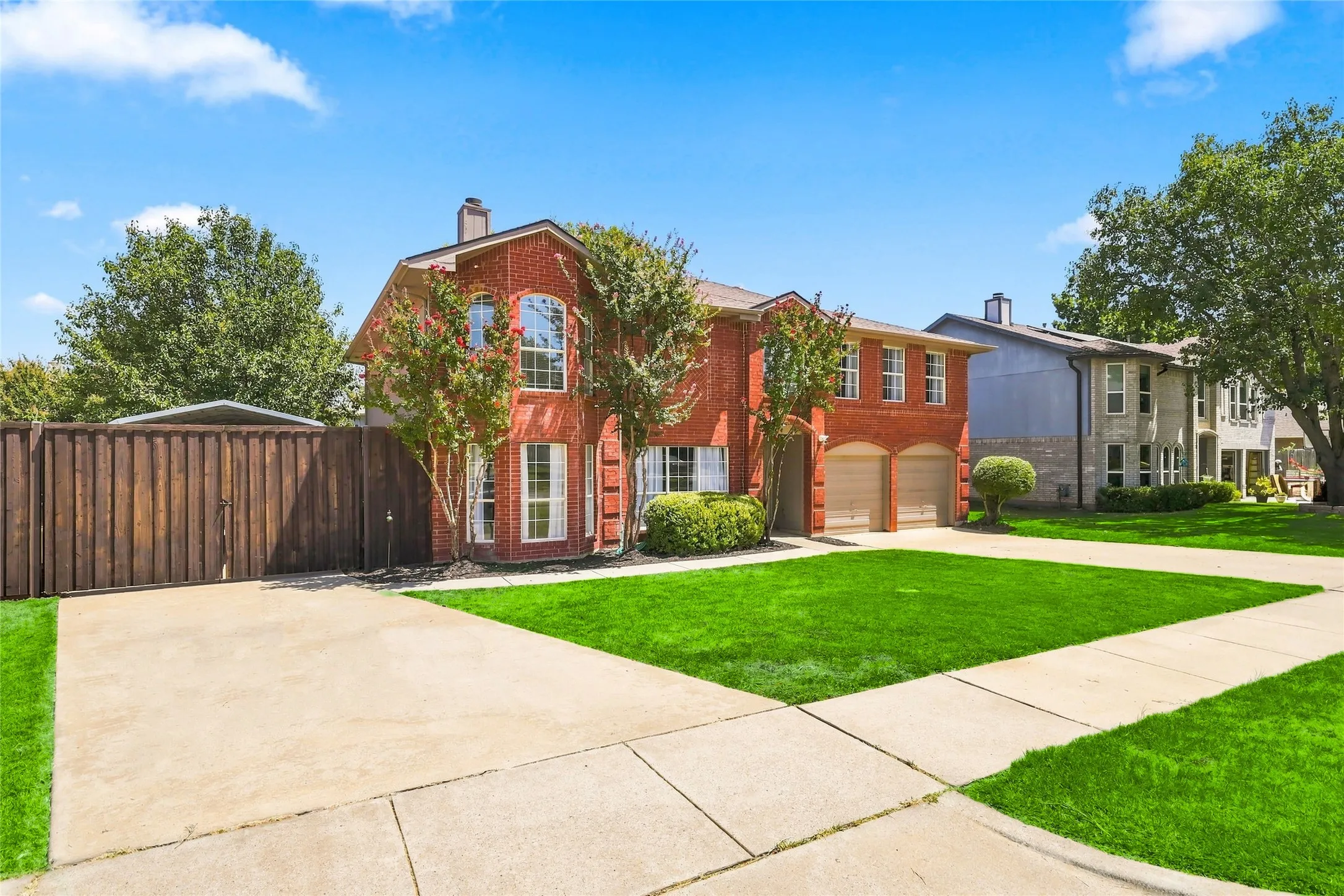 Brick exterior residence with a two-car garage, concrete driveway, and established landscaping