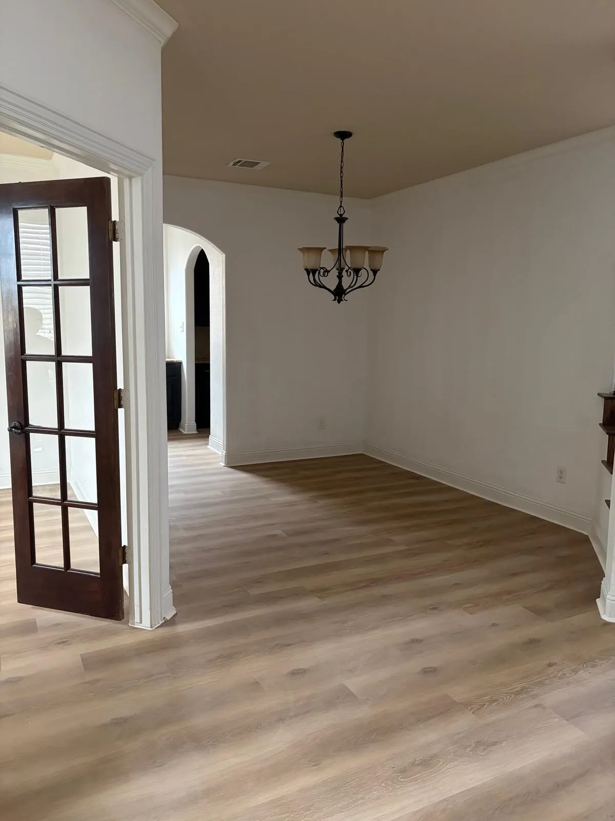 Wood-finish flooring throughout, with crown molding and a dark-finish chandelier