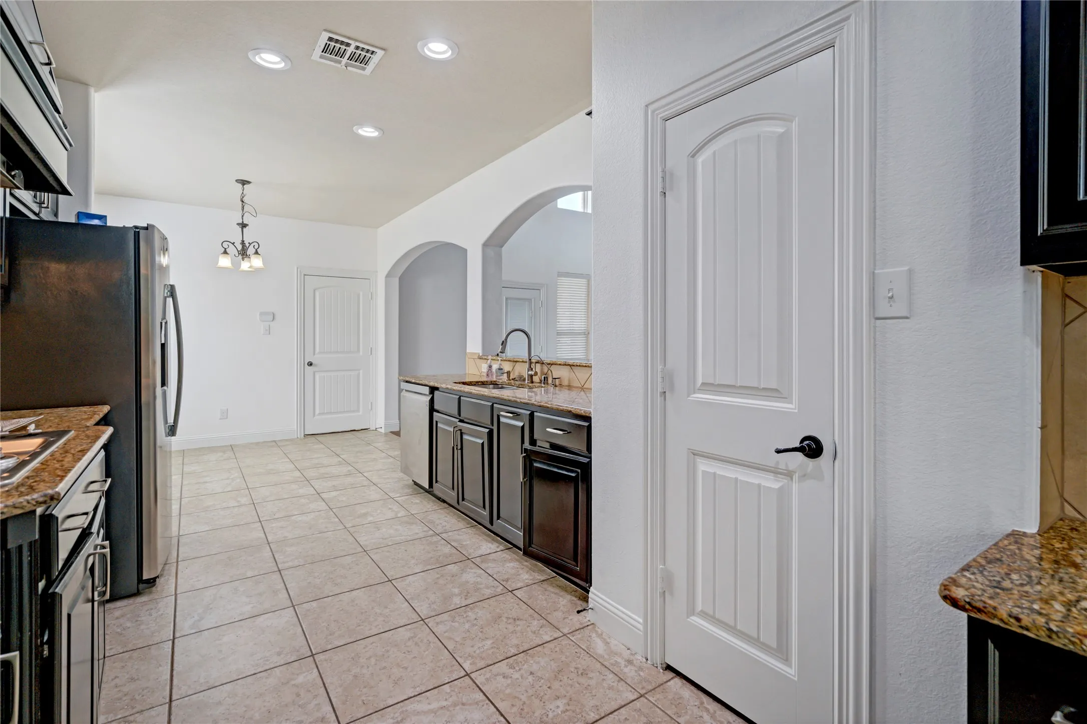 Kitchen with tile flooring, recessed lighting, arched doorways, a built-in dishwasher, and granite countertops