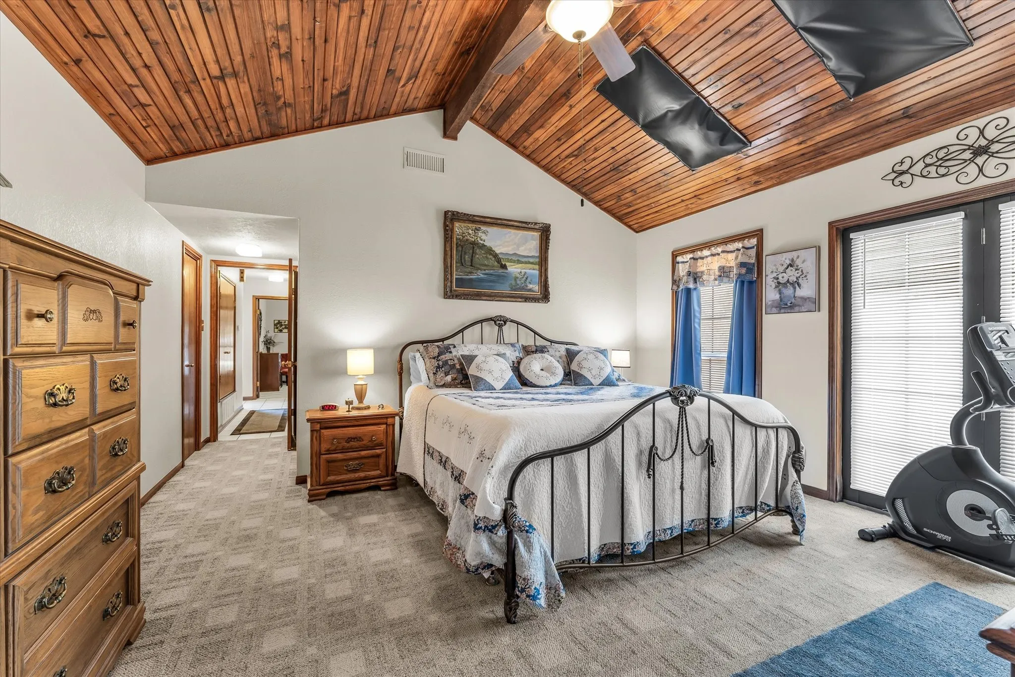 Vaulted wood-paneled ceiling with exposed beams, white walls, and light-toned patterned carpeting