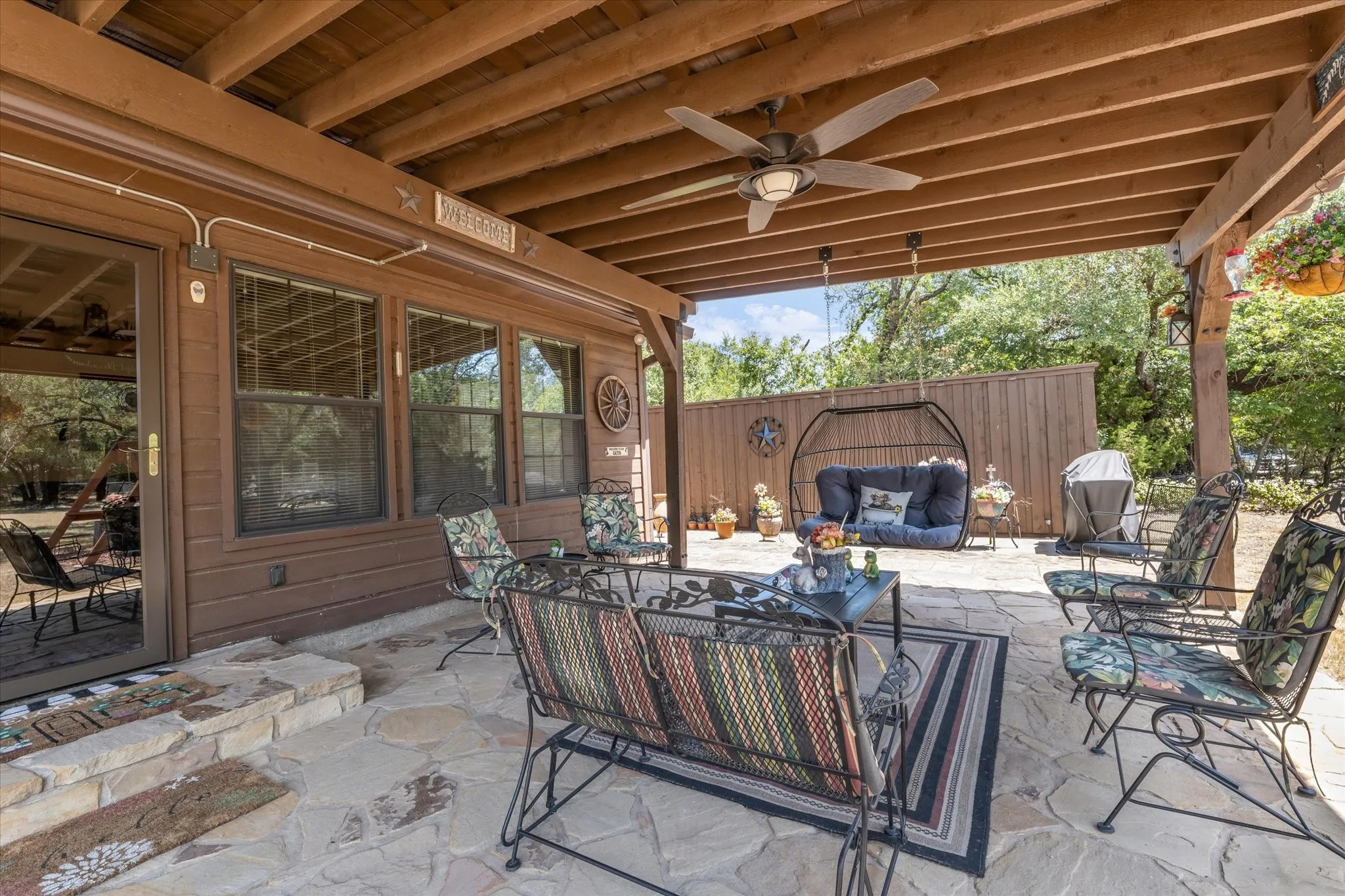 Covered patio featuring an exposed wood beam ceiling, ceiling fan, and flagstone flooring