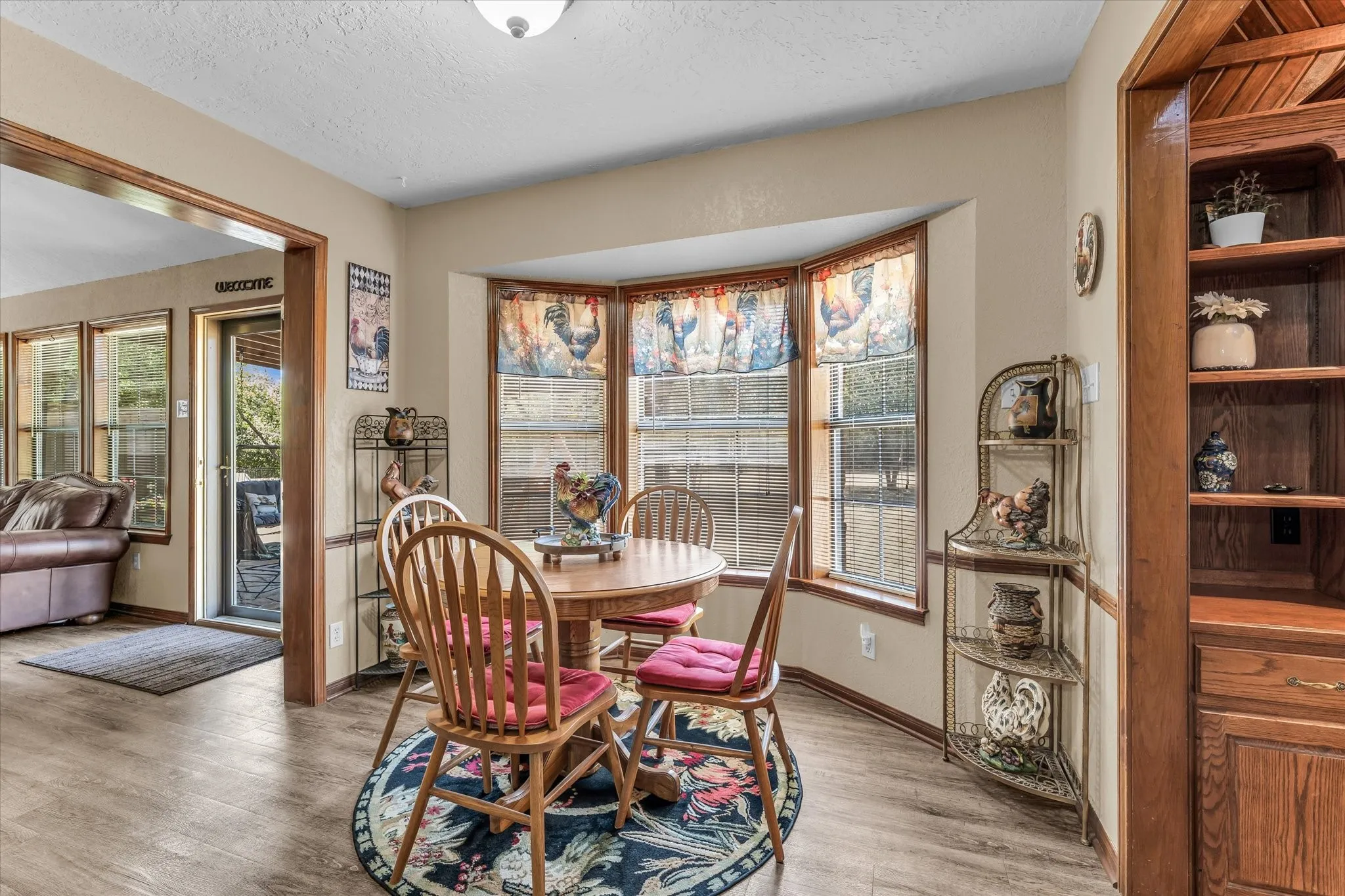 Wood-finish flooring throughout, featuring a bay window, built-in shelving, and wood trim details