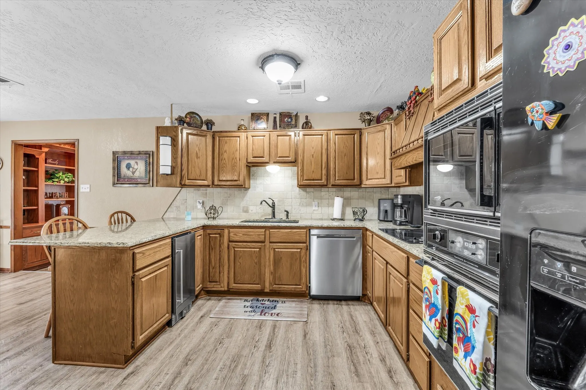 Wood-finish flooring with a U-shaped kitchen layout, featuring wood cabinetry and light-toned countertops