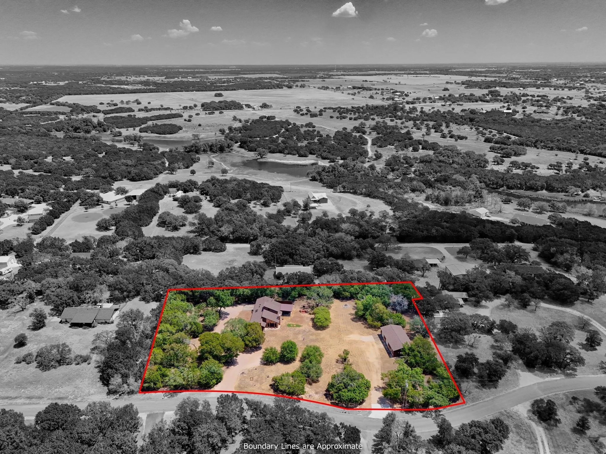 Expansive rural setting with multiple structures, natural tree coverage, and a defined property boundary