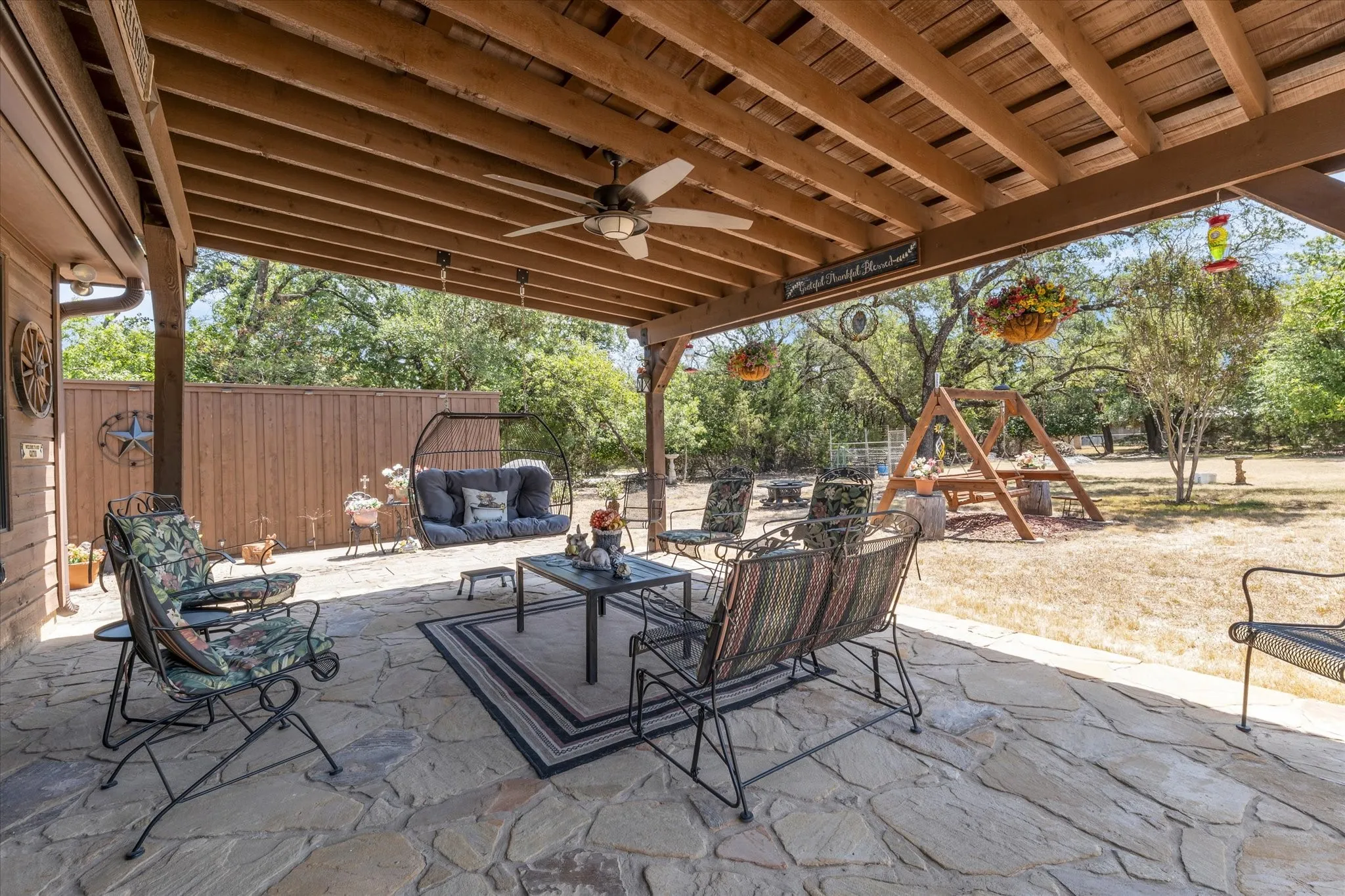 Covered patio featuring a wood-beam ceiling, ceiling fan, and flagstone flooring