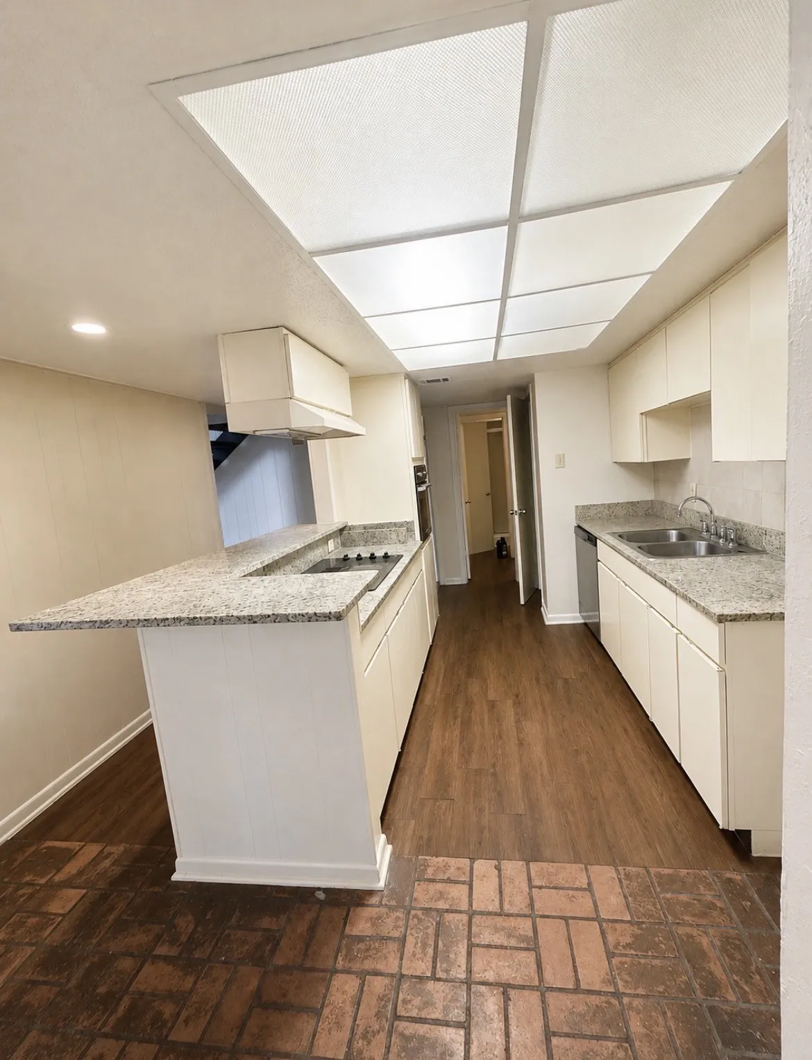 Kitchen featuring wood-finish flooring, white cabinetry, integrated cooktop, and granite counter tops