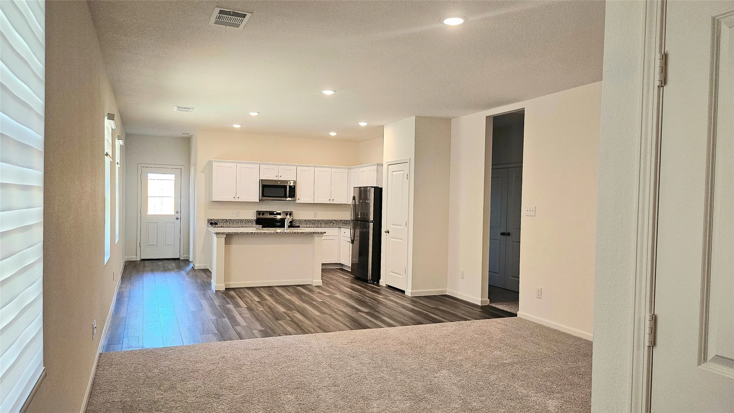 Kitchen featuring white cabinetry, dark stone countertops, an island with seating, and recessed lighting