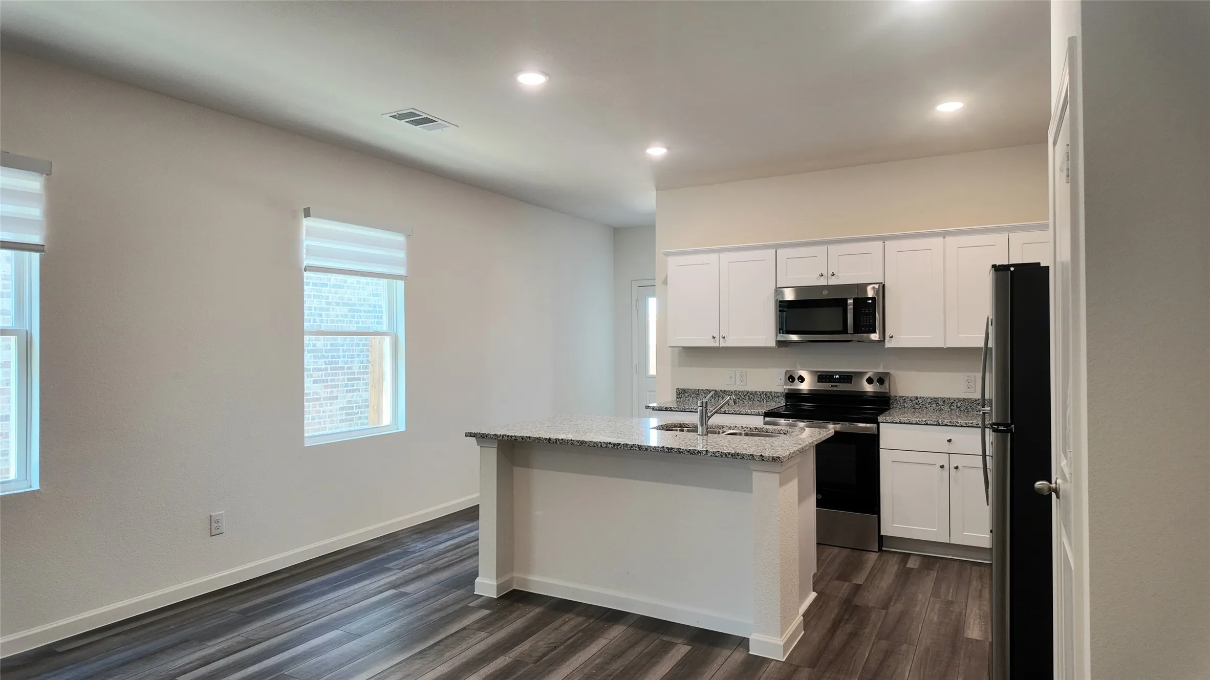Kitchen featuring white cabinetry, a built-in microwave, a range, and a refrigerator