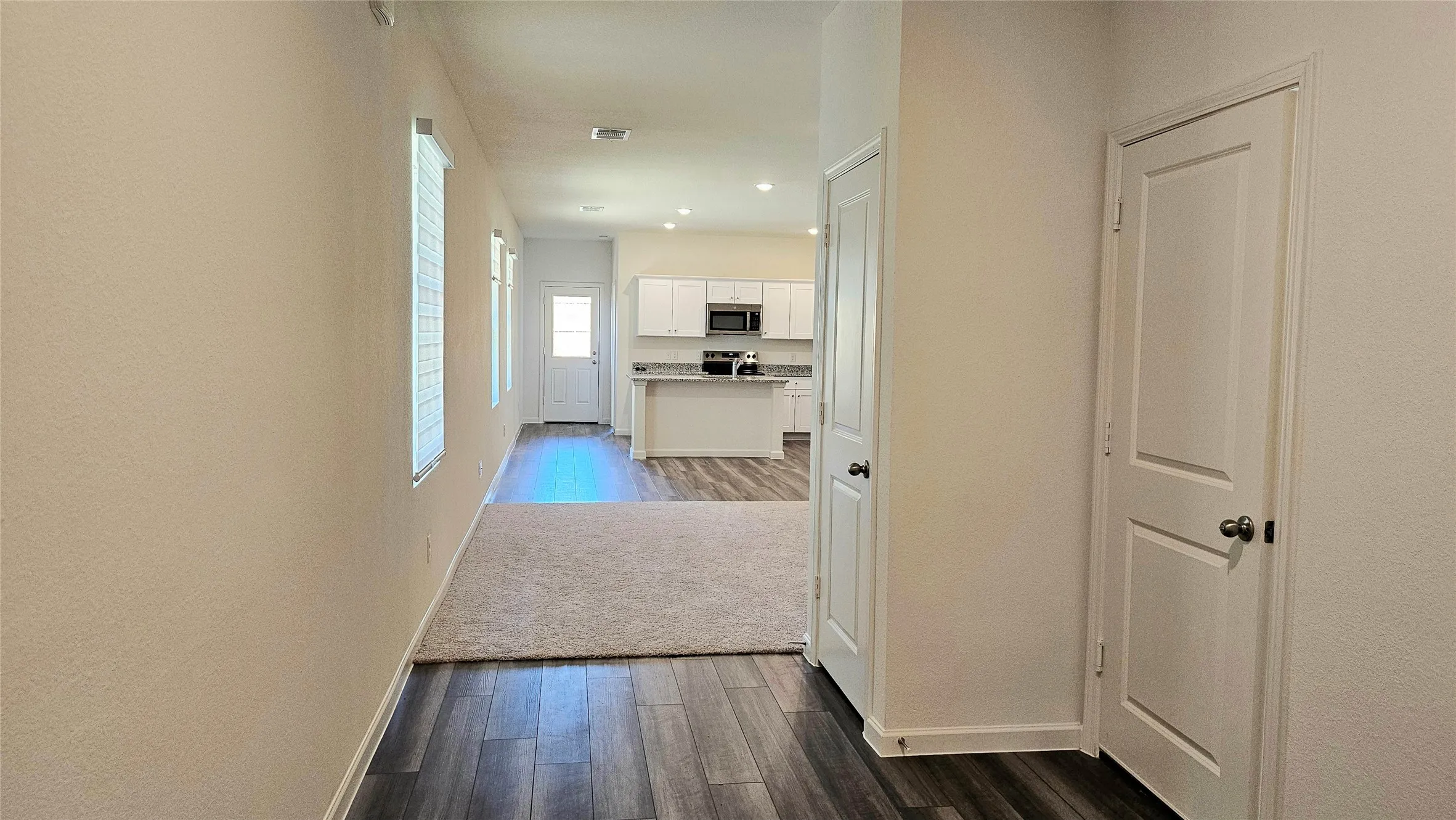 Wood-finish flooring, recessed lighting, and white paneled doors