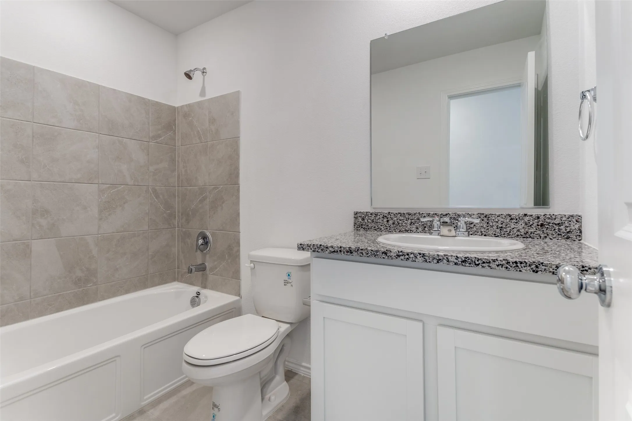Full bathroom with tiled shower / bath combo, toilet, and large vanity