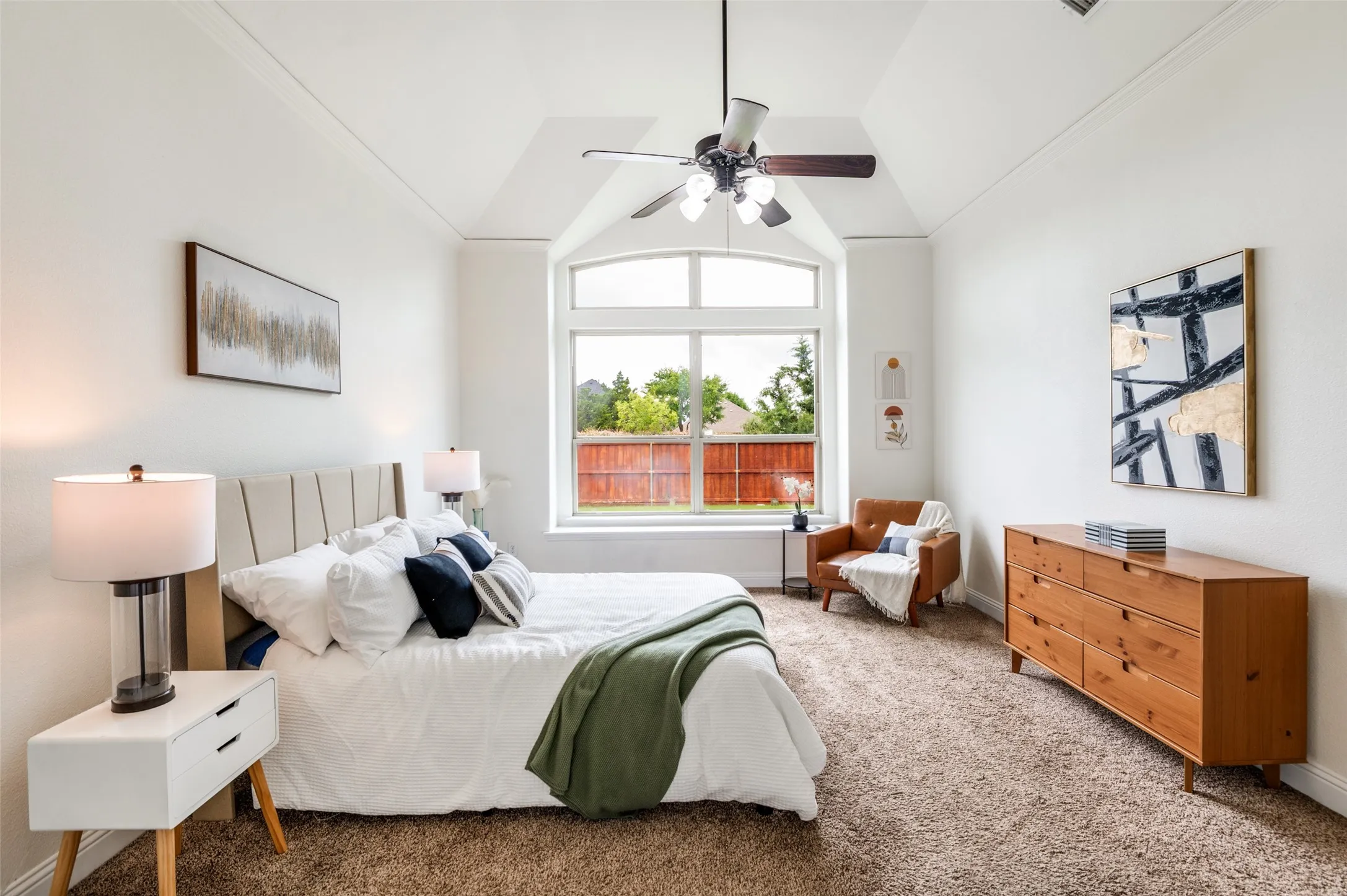 Vaulted ceiling with an attached ceiling fan, arched window with multiple panes, and wall-to-wall carpeting