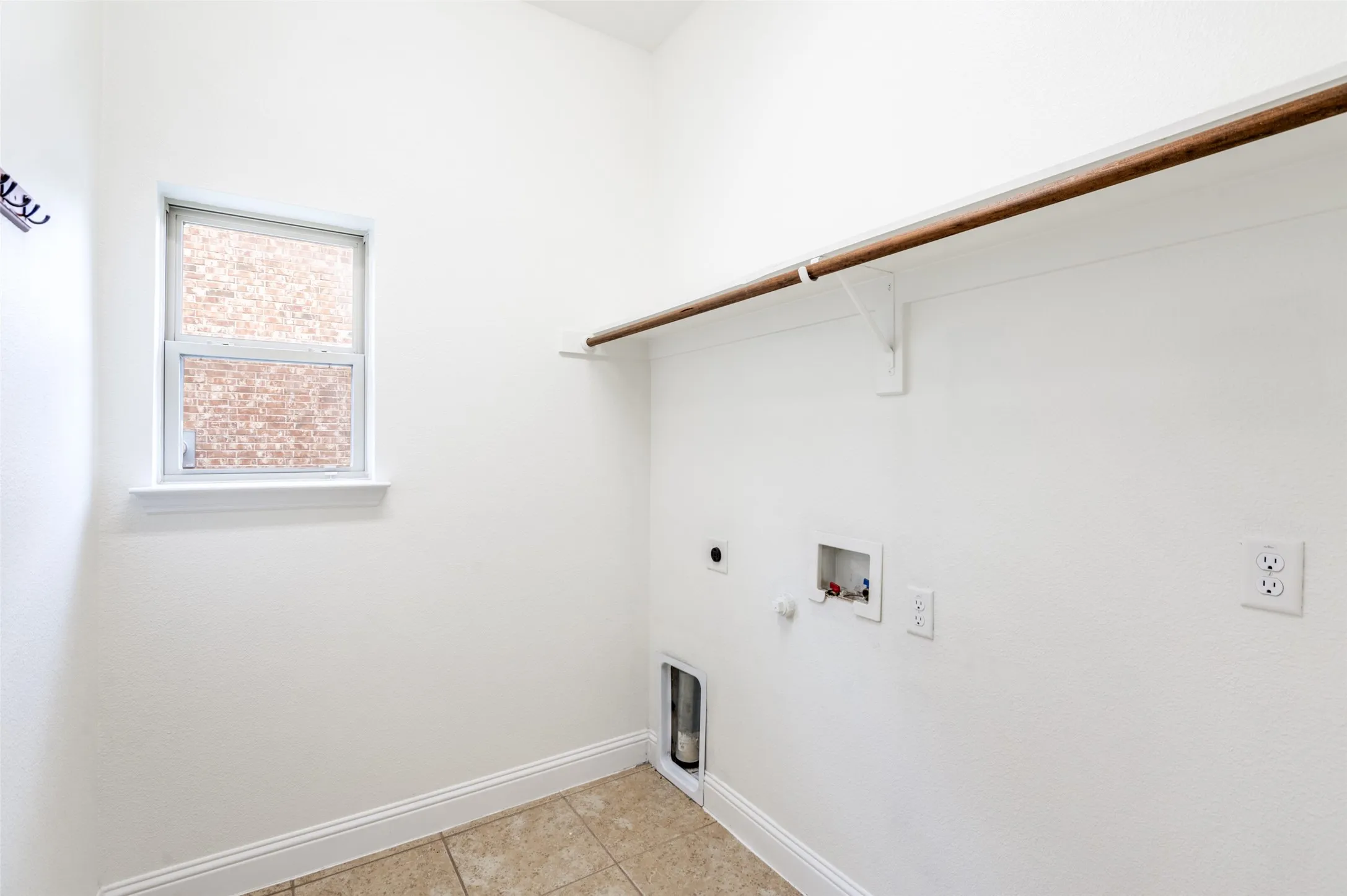 Laundry area featuring a window, built-in shelving, a clothes rod, and tile flooring