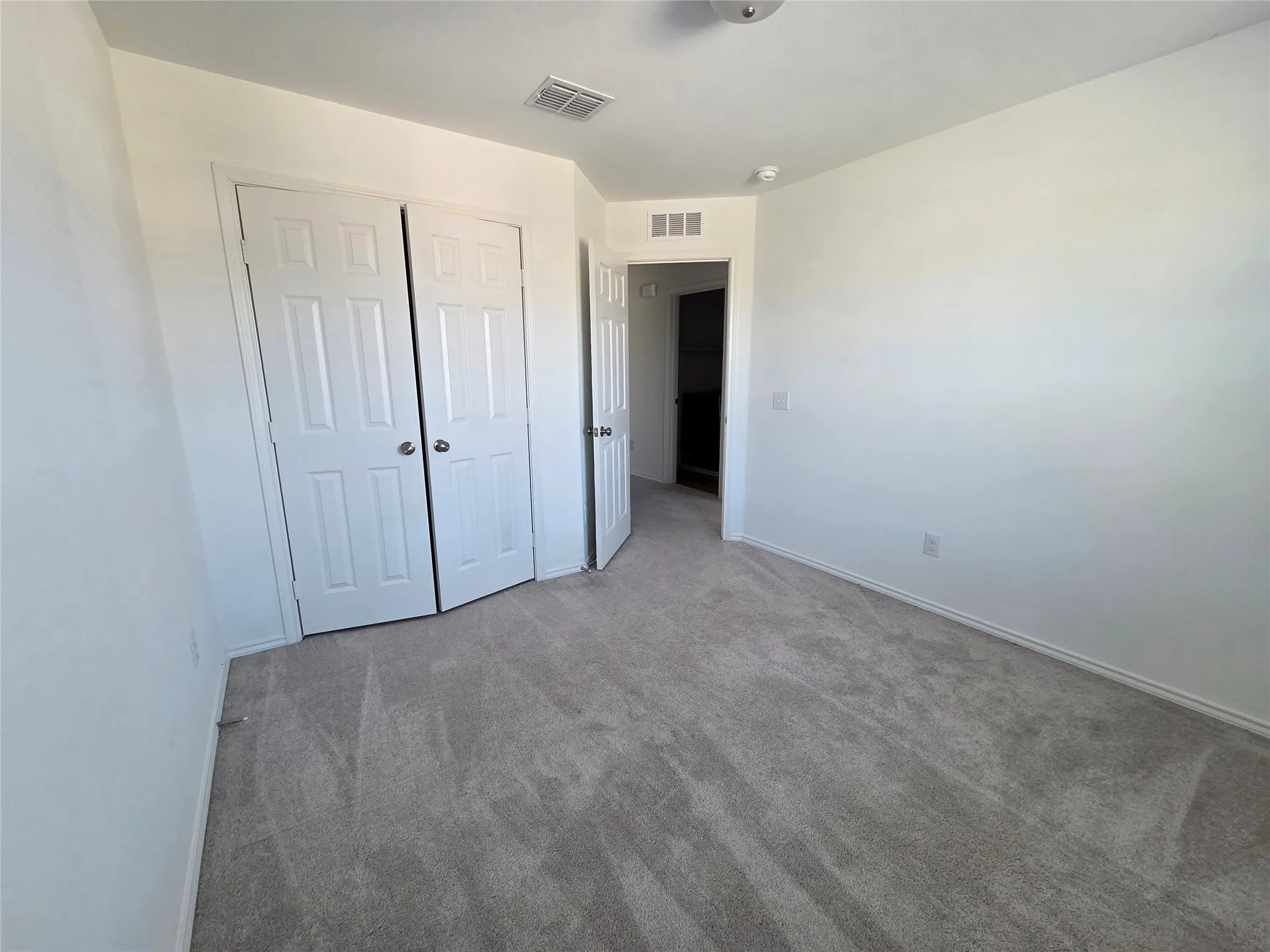 Neutral wall paint, light-colored carpet, white bi-fold closet doors, and recessed lighting
