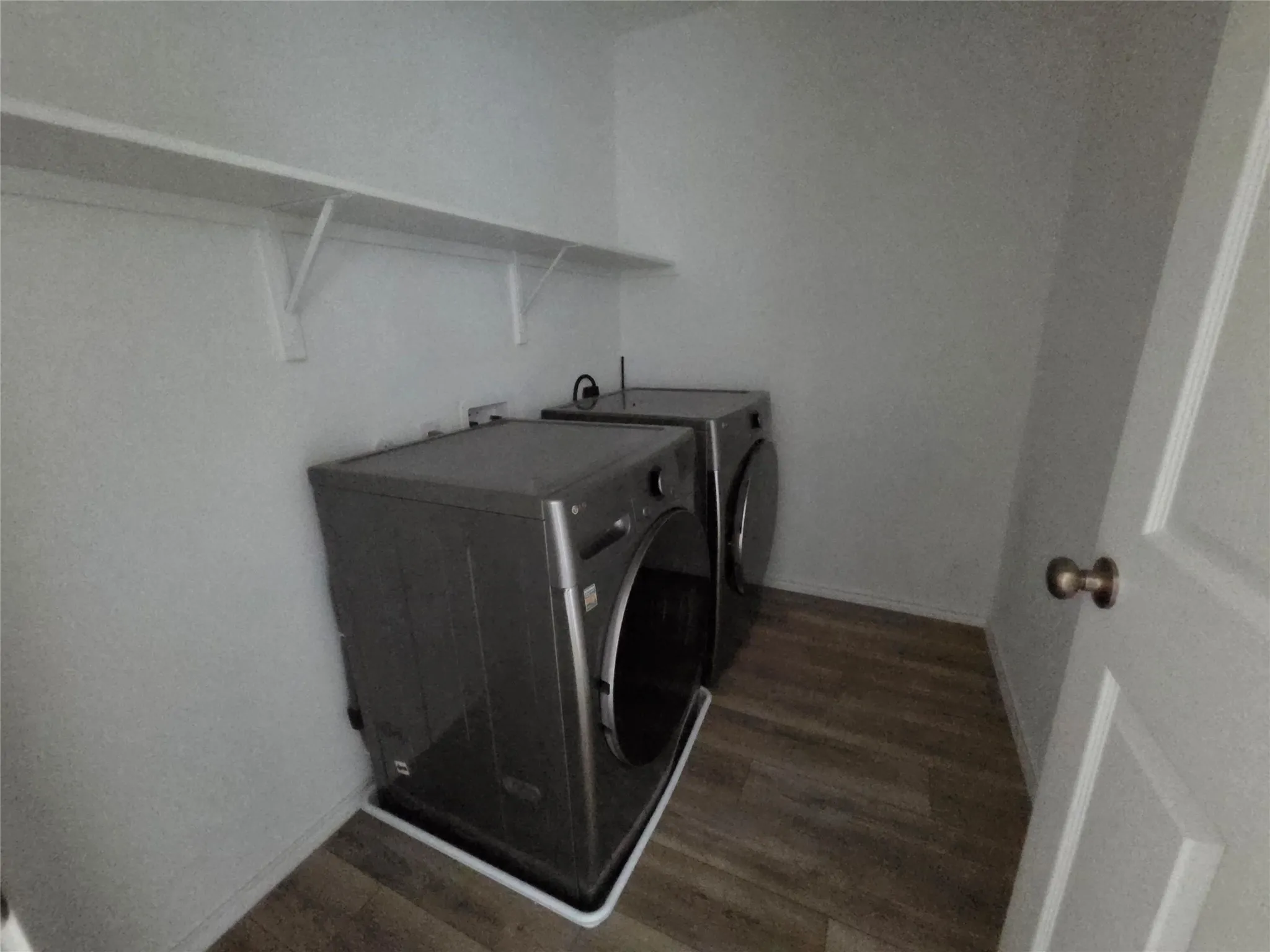 Laundry area with wood-finish flooring and integrated shelving