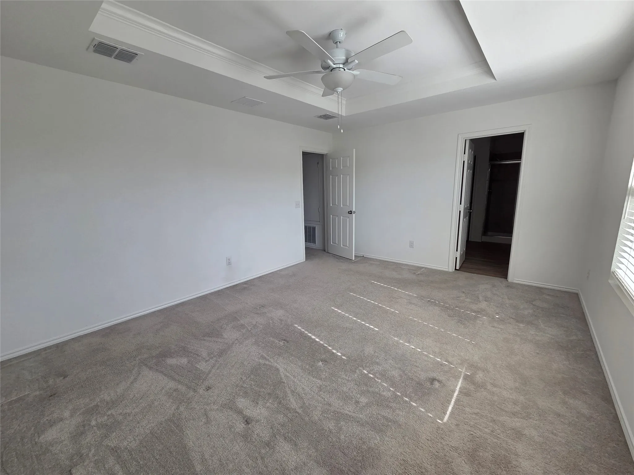 Tray ceiling with crown molding, ceiling fan, carpeted flooring, and window blinds