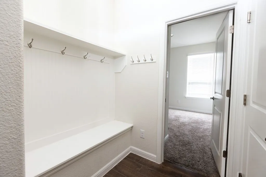 Built-in bench with coat hooks, wood-finish flooring, and crisp white trim