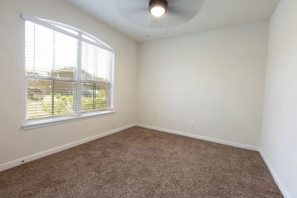 Arched window with blinds, ceiling fan with integrated lighting, wall-to-wall carpeting, and neutral wall paint