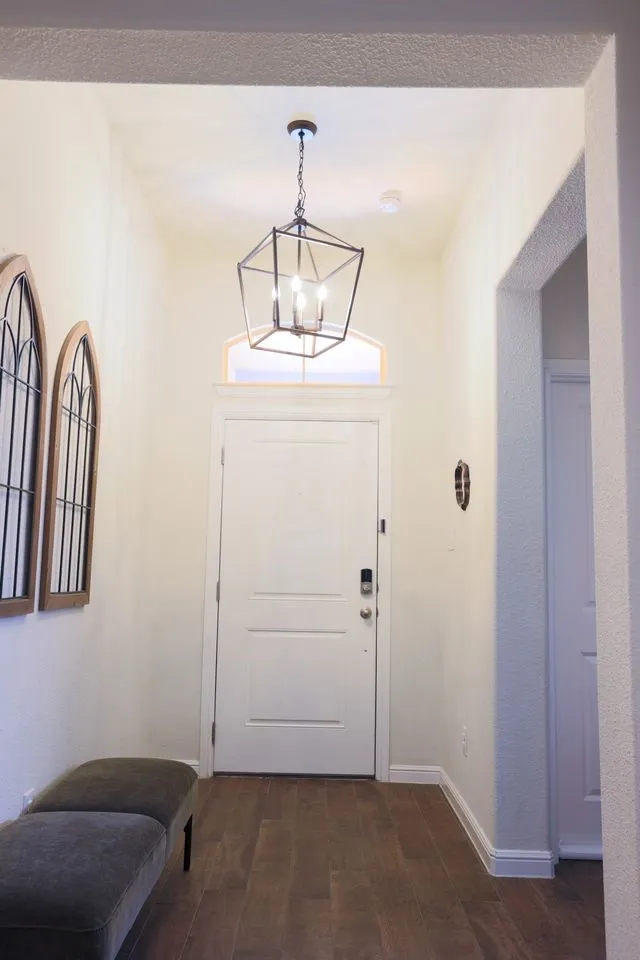 Transitional entryway featuring wood-finish flooring, a contemporary geometric chandelier, and an arched transom window above the entry door