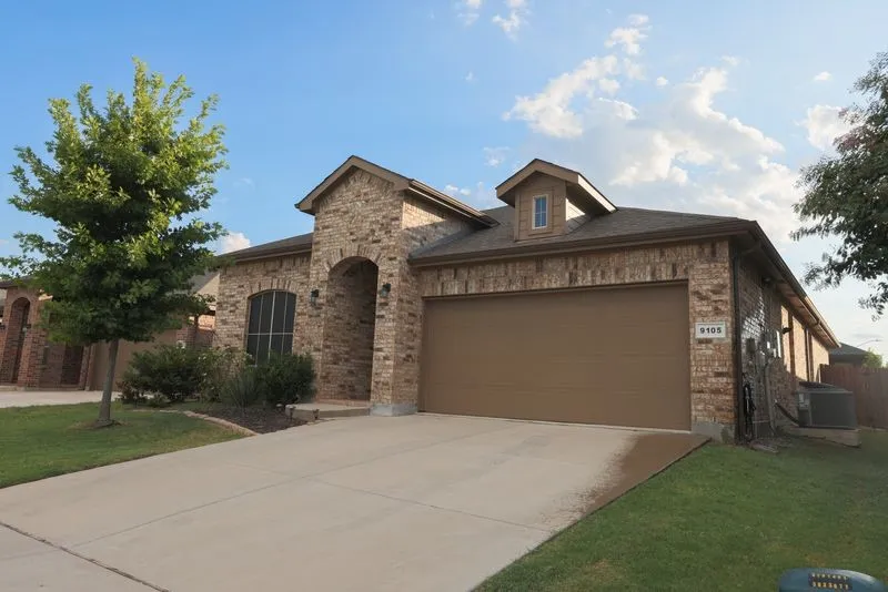 Brick exterior with an arched entry, dormer window, and an attached garage