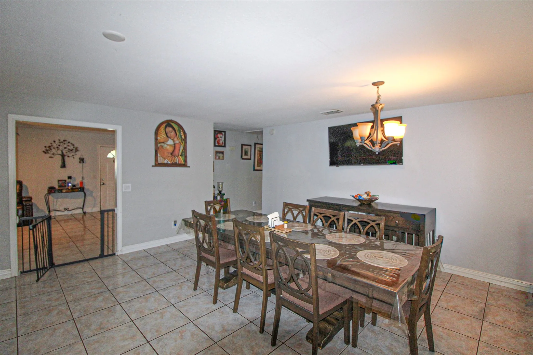 Recessed ceiling lighting, tiled flooring, cased opening, wall-mounted television, and a decorative chandelier