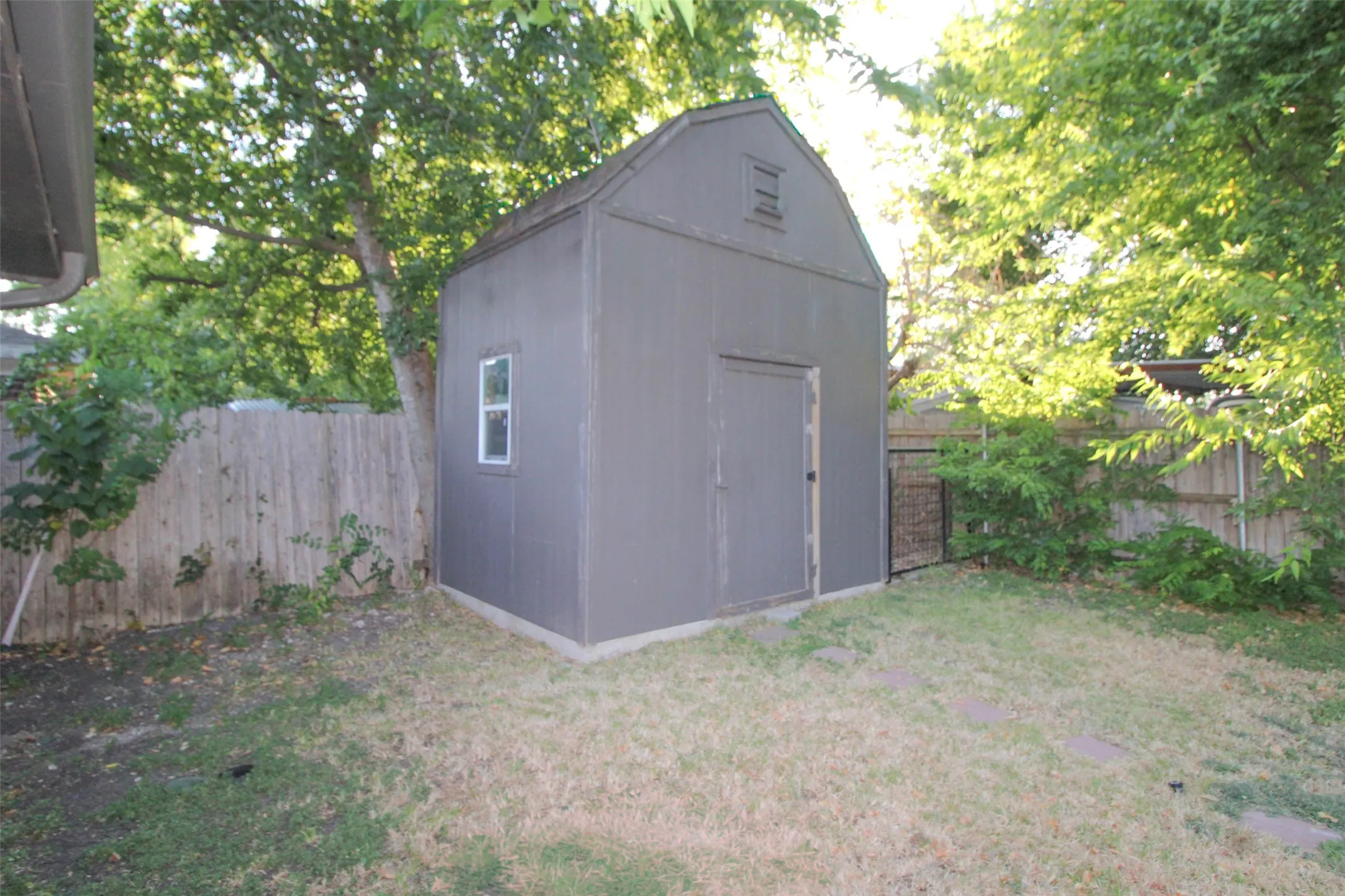 Wood-sided storage shed with a gambrel roof and a single window
