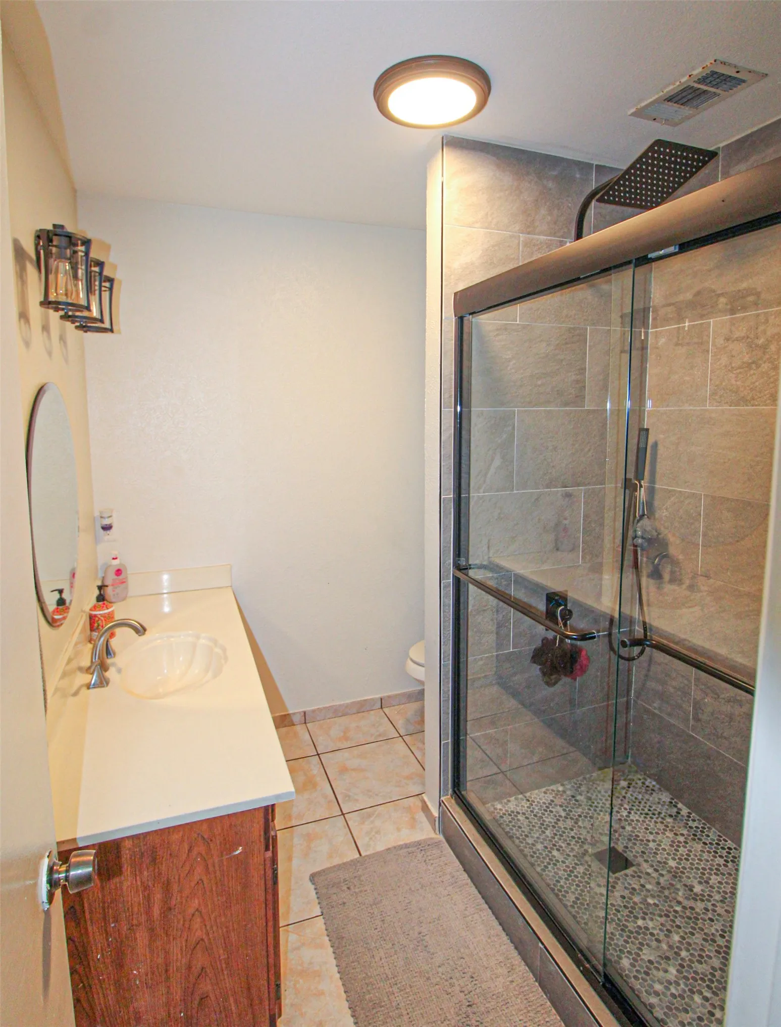 Walk-in shower with glass enclosure, rain shower head, and mosaic tile shower floor