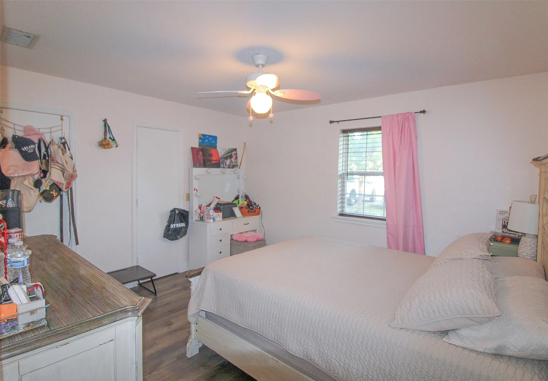 White walls, wood-finish flooring, and a ceiling fan with integrated lighting