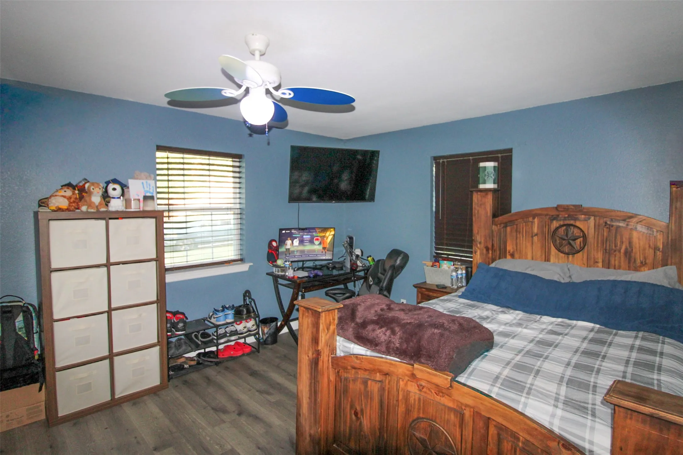 Wood-finish flooring with dual windows and a ceiling fan with integrated lighting