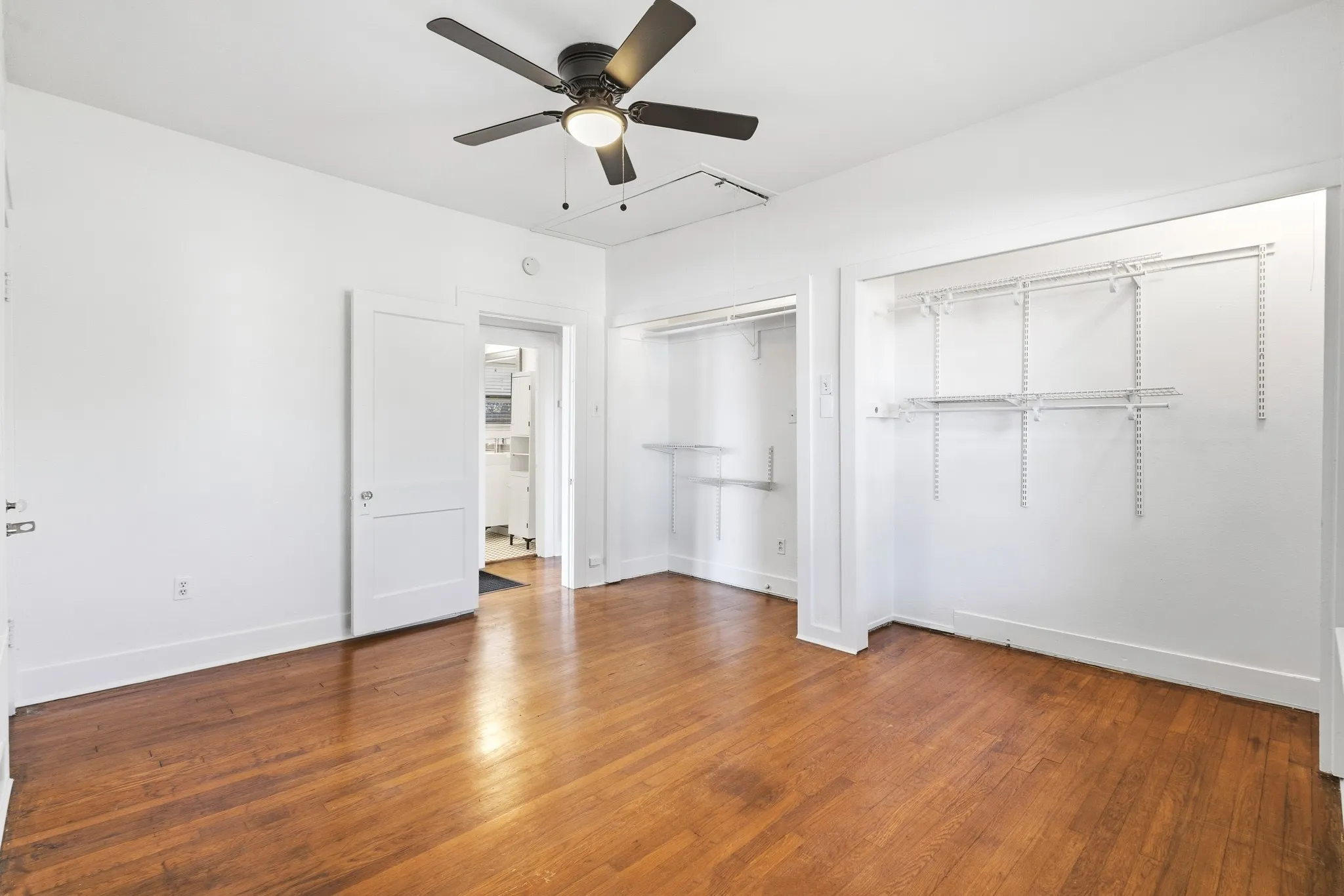 Hardwood flooring throughout, ceiling fan with integrated lighting, and multiple open closet systems